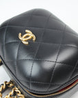 Chanel Matelassé Vanity Shoulder Bag in black leather with gold chain strap and quilted design, displayed on a white surface.