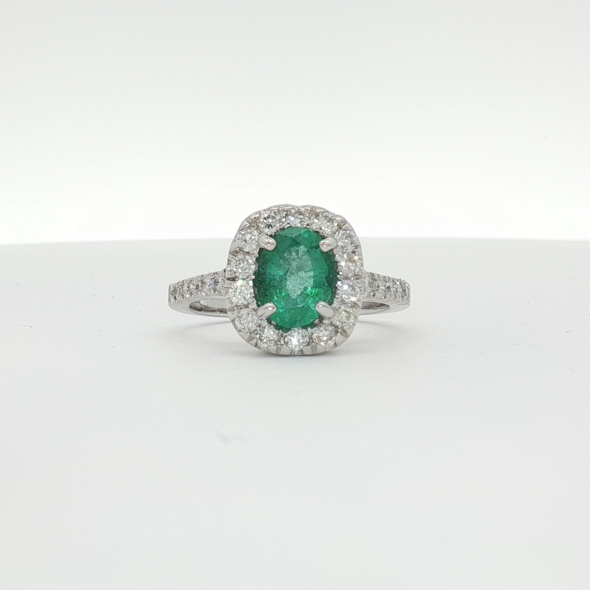 14K white gold emerald and diamond halo ring with intricate design, featuring a central emerald surrounded by sparkling diamonds.