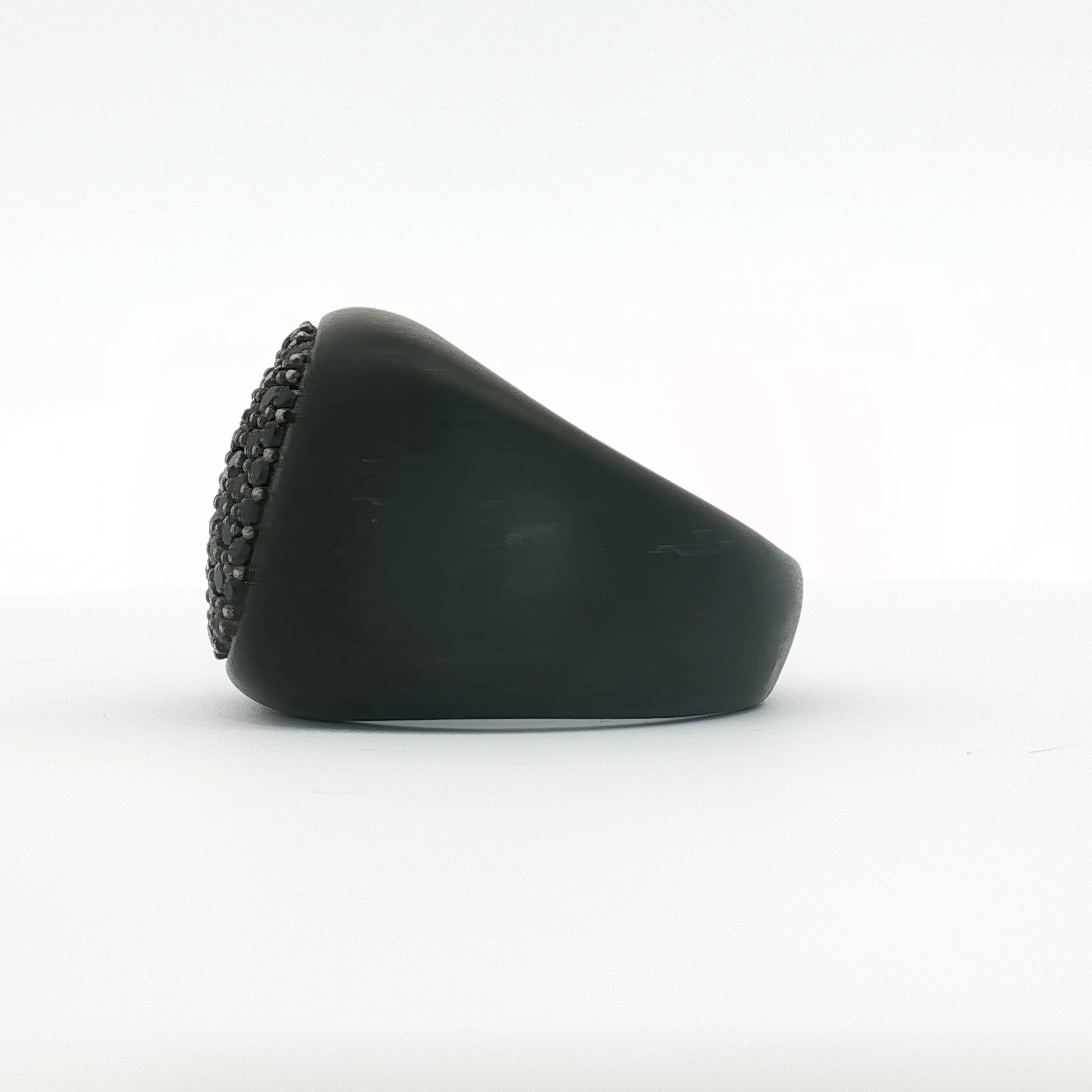 Black diamond signet ring from David Yurman featuring a sleek gold band, displayed on a jewelry stand with a blurred background.