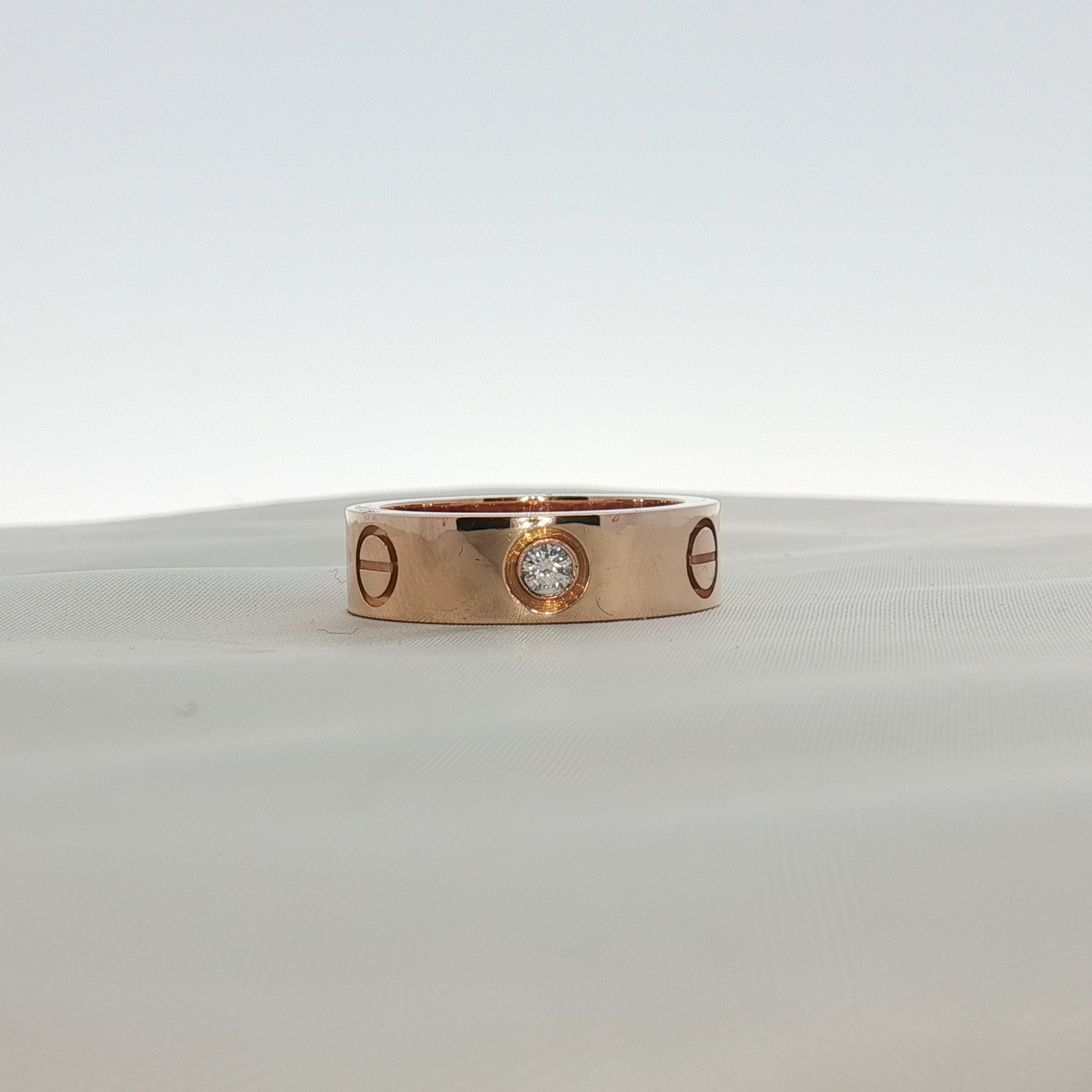 Cartier Love diamond ring shown in gold jewelry with embedded sparkling diamonds on a white background.