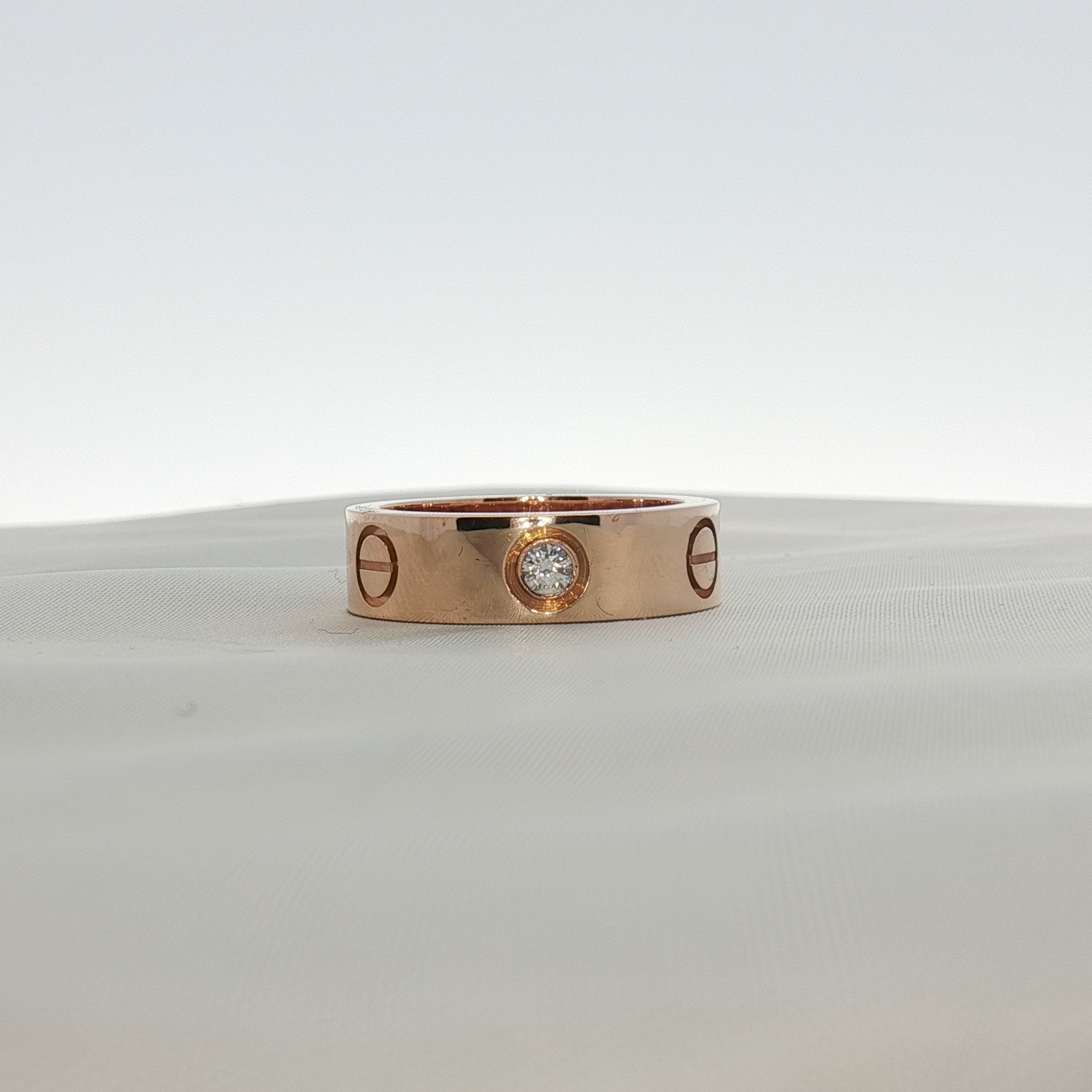 Cartier Love diamond ring shown in gold jewelry with embedded sparkling diamonds on a white background.