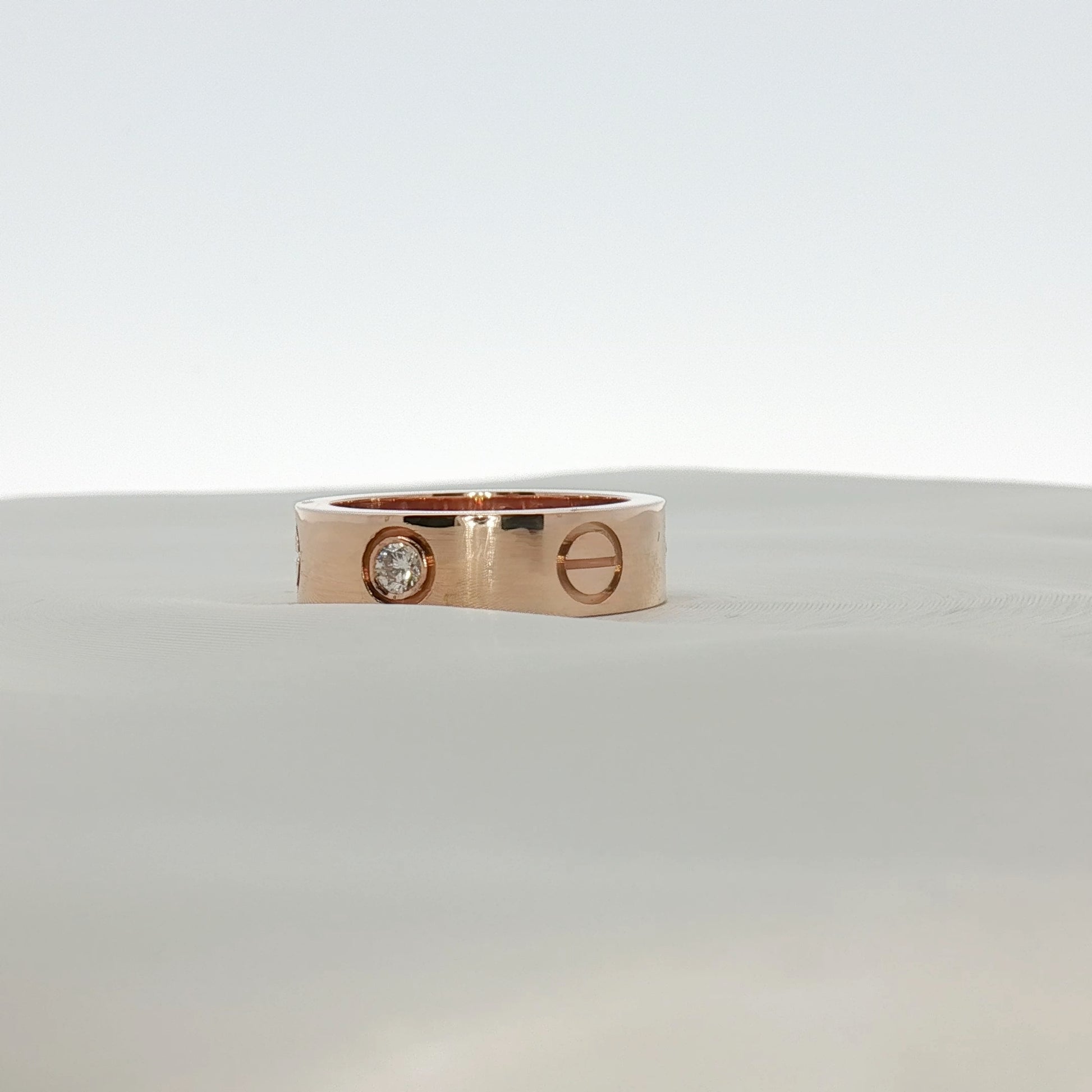 Cartier Love Diamond Ring featuring gold band with embedded diamonds, elegant jewelry piece displayed on a neutral background