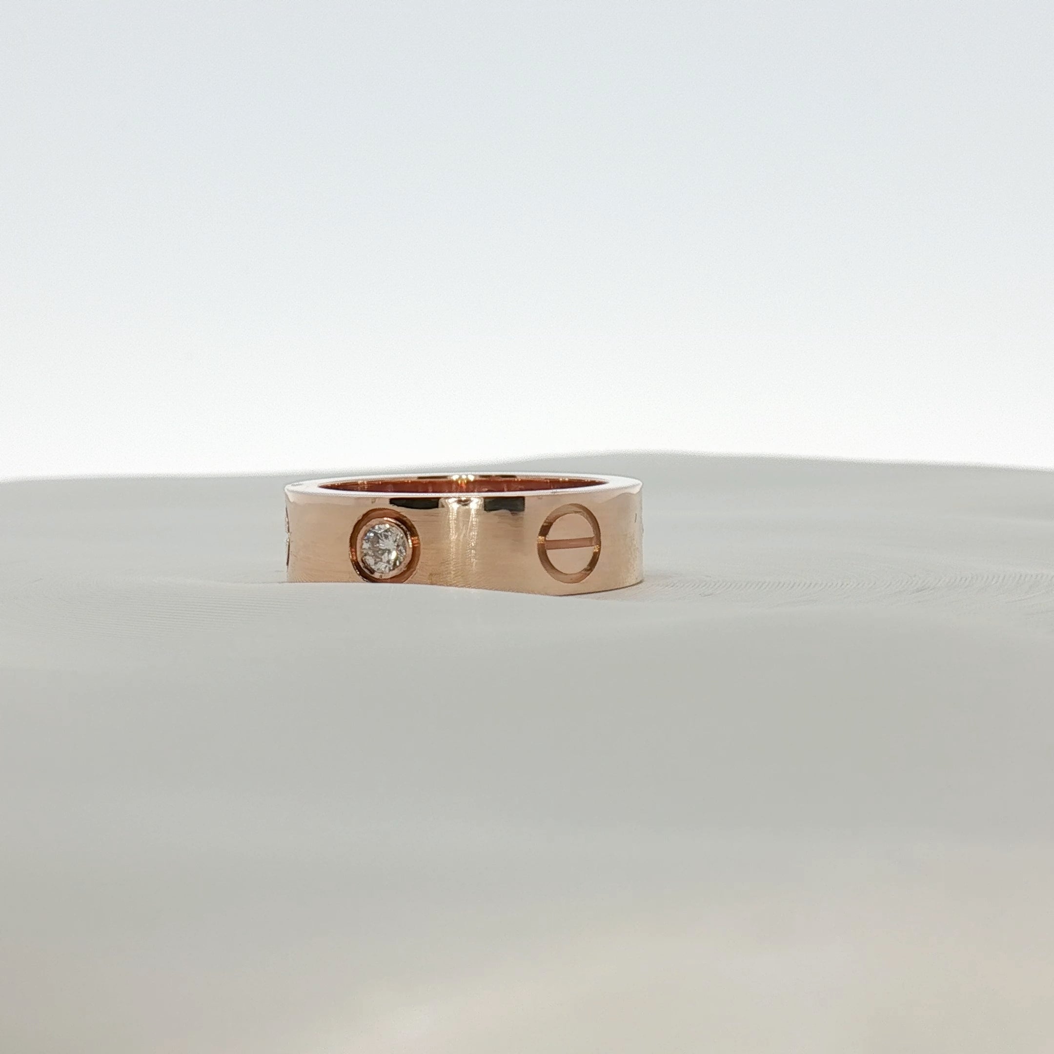 Cartier Love Diamond Ring featuring gold band with embedded diamonds, elegant jewelry piece displayed on a neutral background