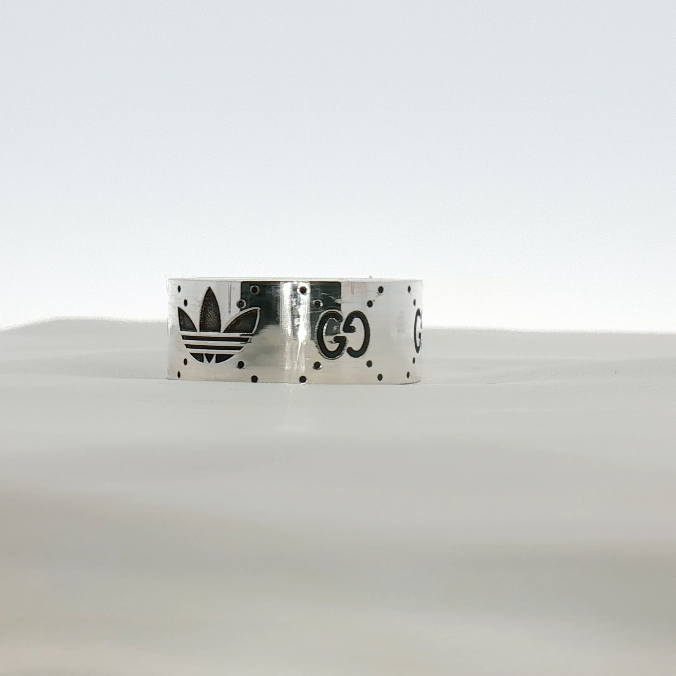 Gold & Beyond Gucci x Adidas logo band ring featuring a sleek jewelry design with iconic brand logos.