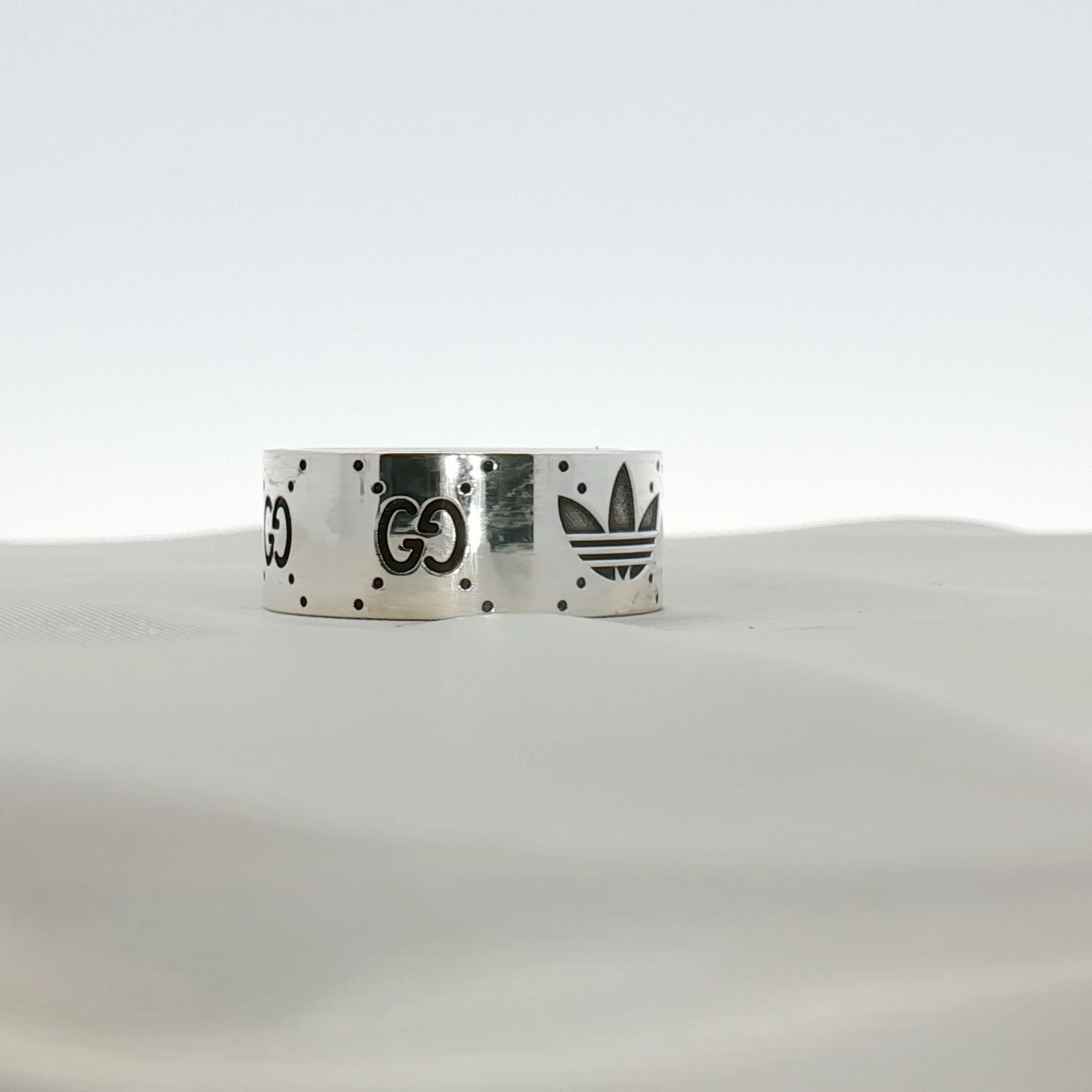 Gold & Beyond Gucci x Adidas logo band ring, stainless steel jewelry with iconic brand logos and sleek design.
