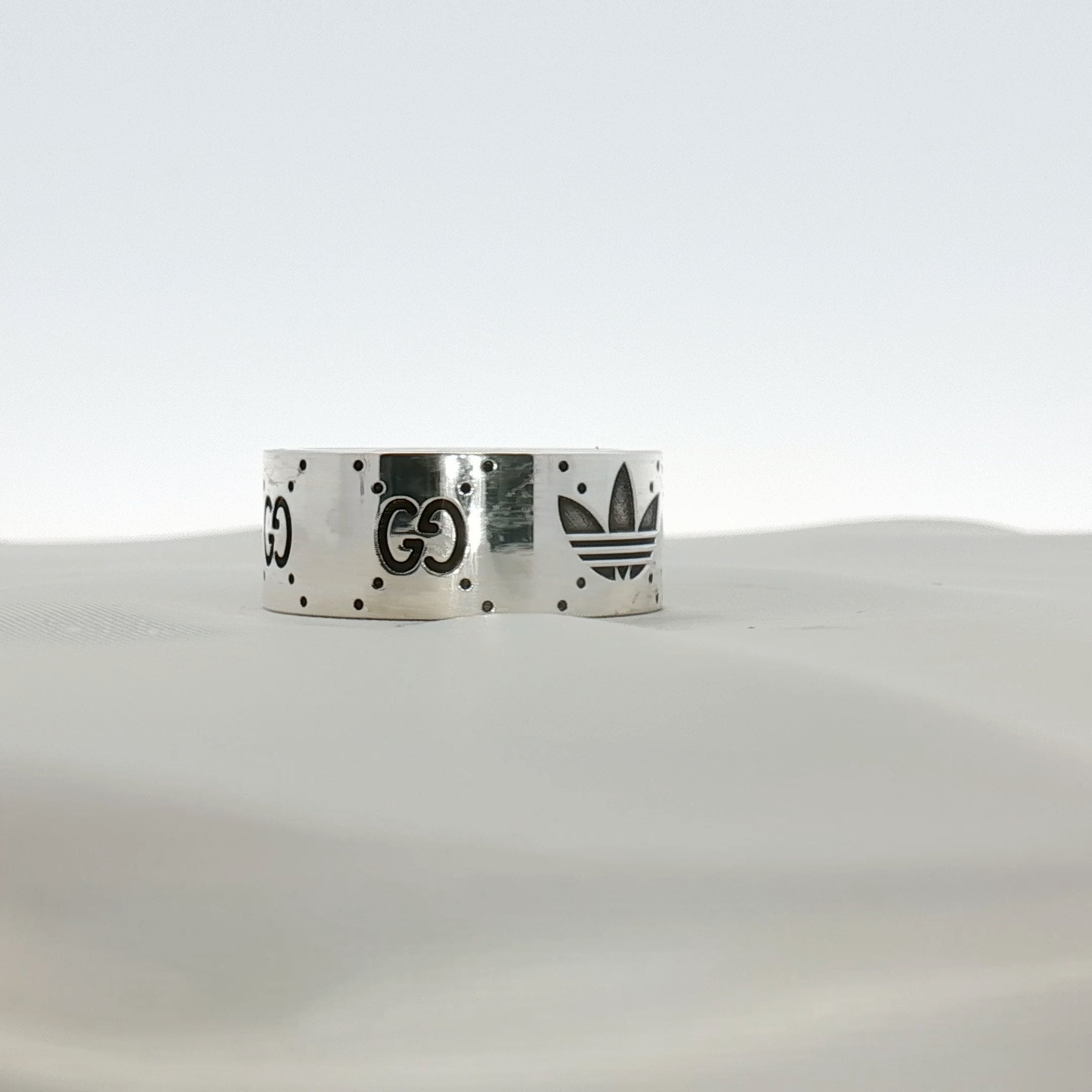 Gold & Beyond Gucci x Adidas logo band ring, stainless steel jewelry with iconic brand logos and sleek design.