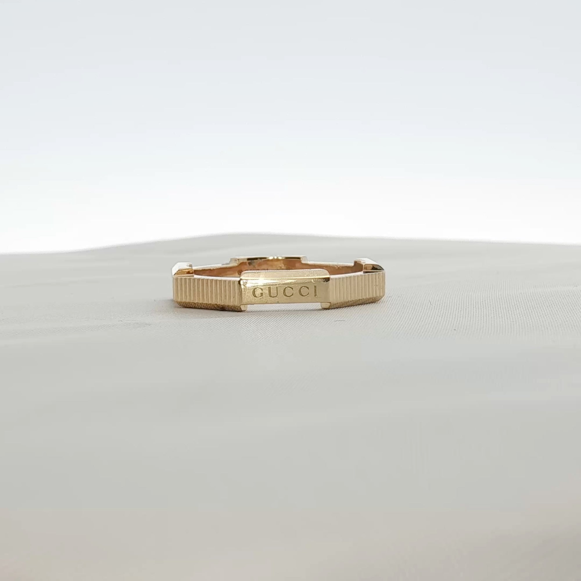 Gold & Beyond Gucci Link to Love striped jewelry ring with bold red, white, and black design, featuring a sleek gold band.