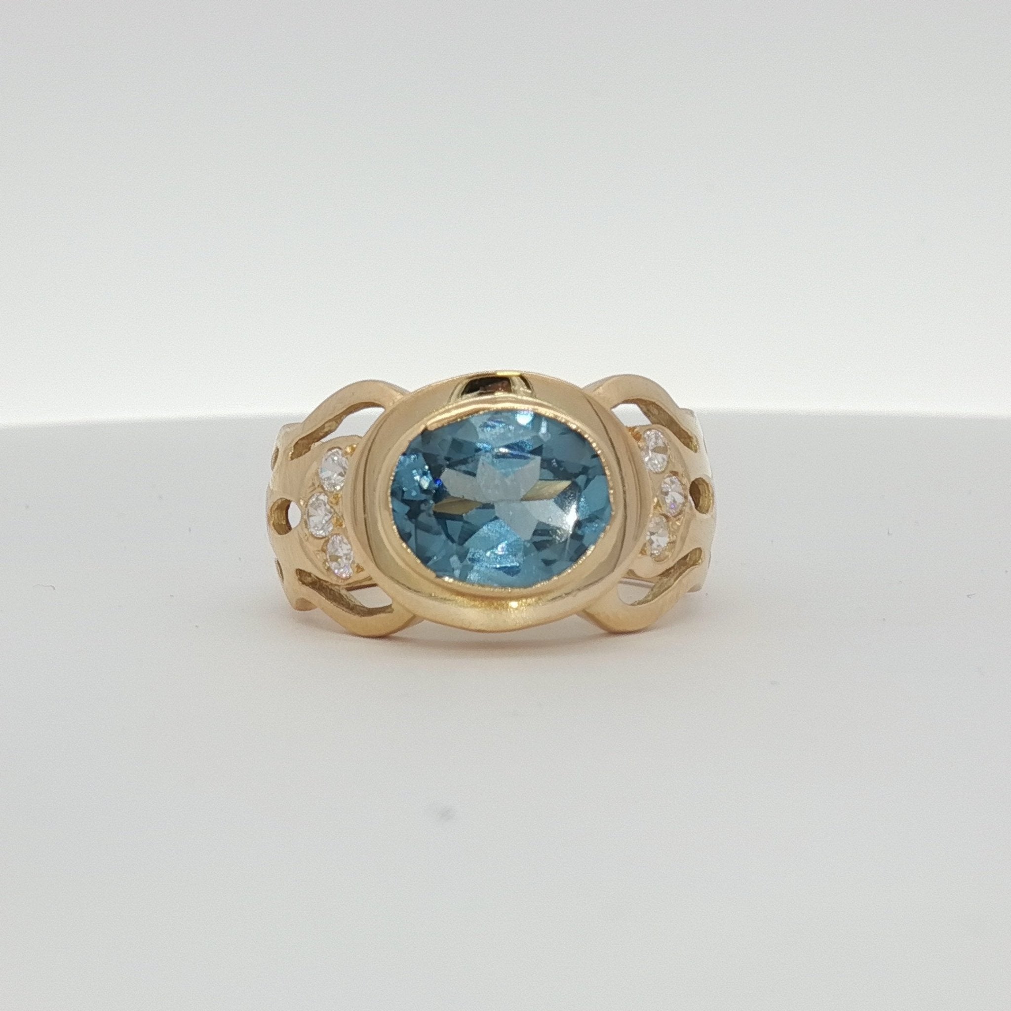 18K yellow gold oval blue gemstone and diamond ring from Gold & Beyond with intricate design and sparkling accents.