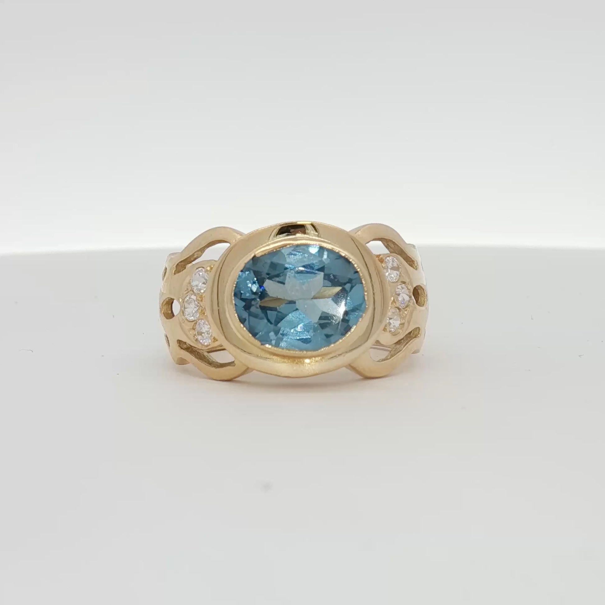 18K yellow gold oval blue gemstone and diamond jewelry ring with intricate design, featuring a vibrant blue center stone and sparkling accents.