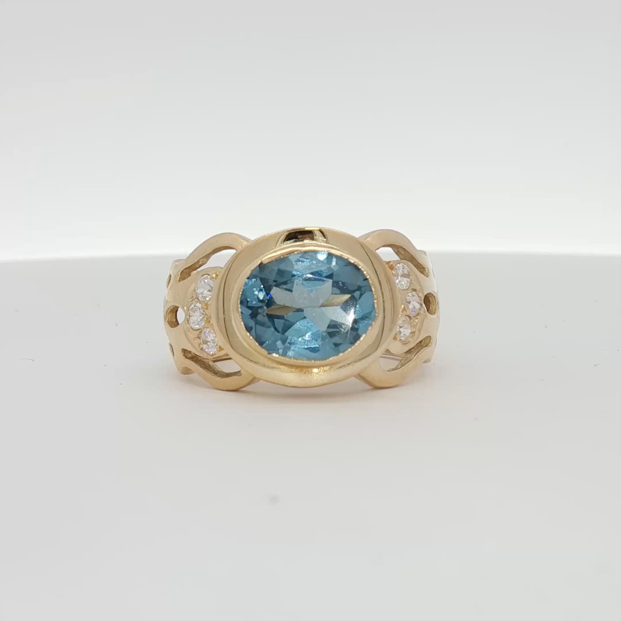 18K yellow gold oval blue gemstone and diamond ring with intricate detailing, showcasing elegant jewelry design.