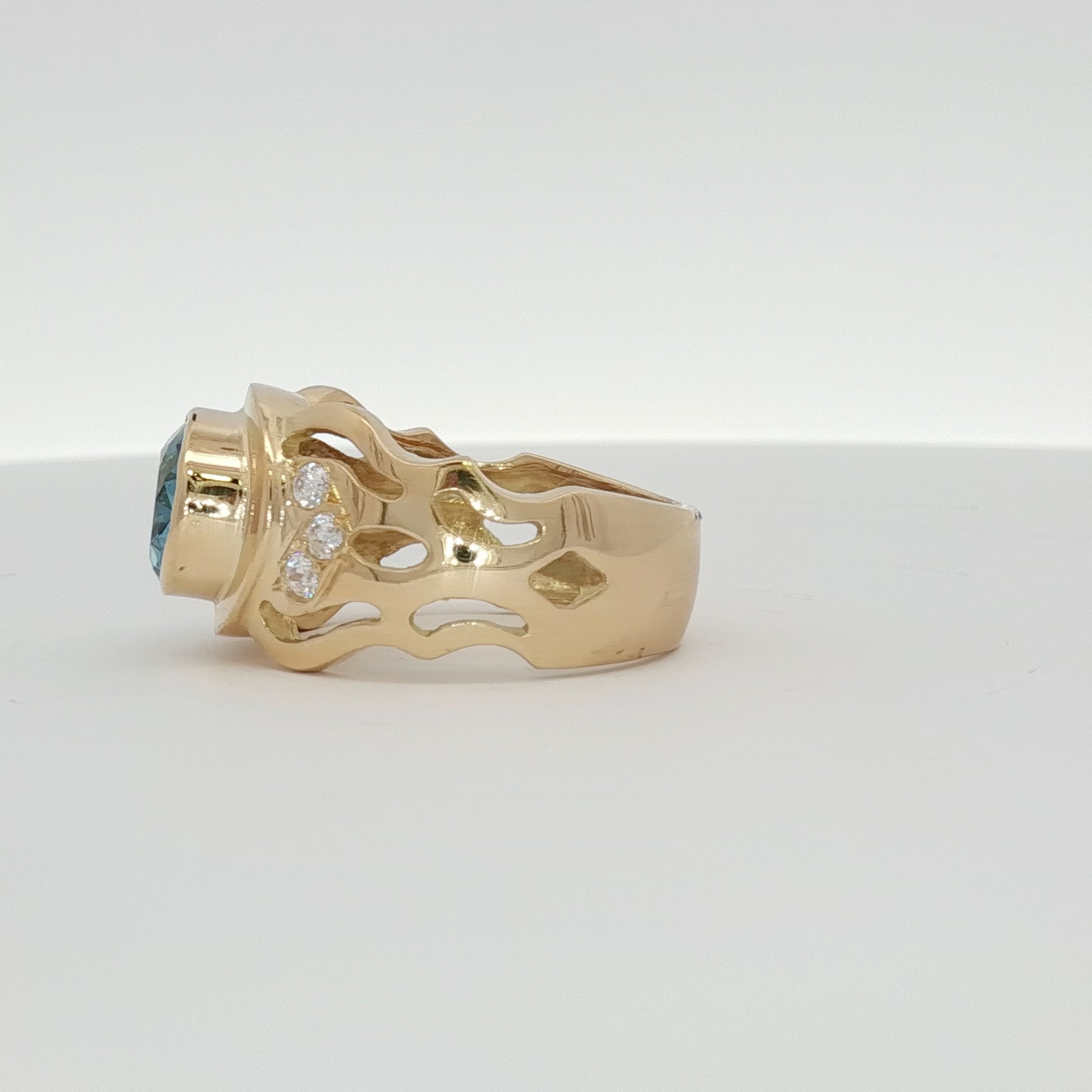 18K yellow gold oval blue gemstone and diamond ring with intricate band design, showcasing luxurious jewelry craftsmanship.