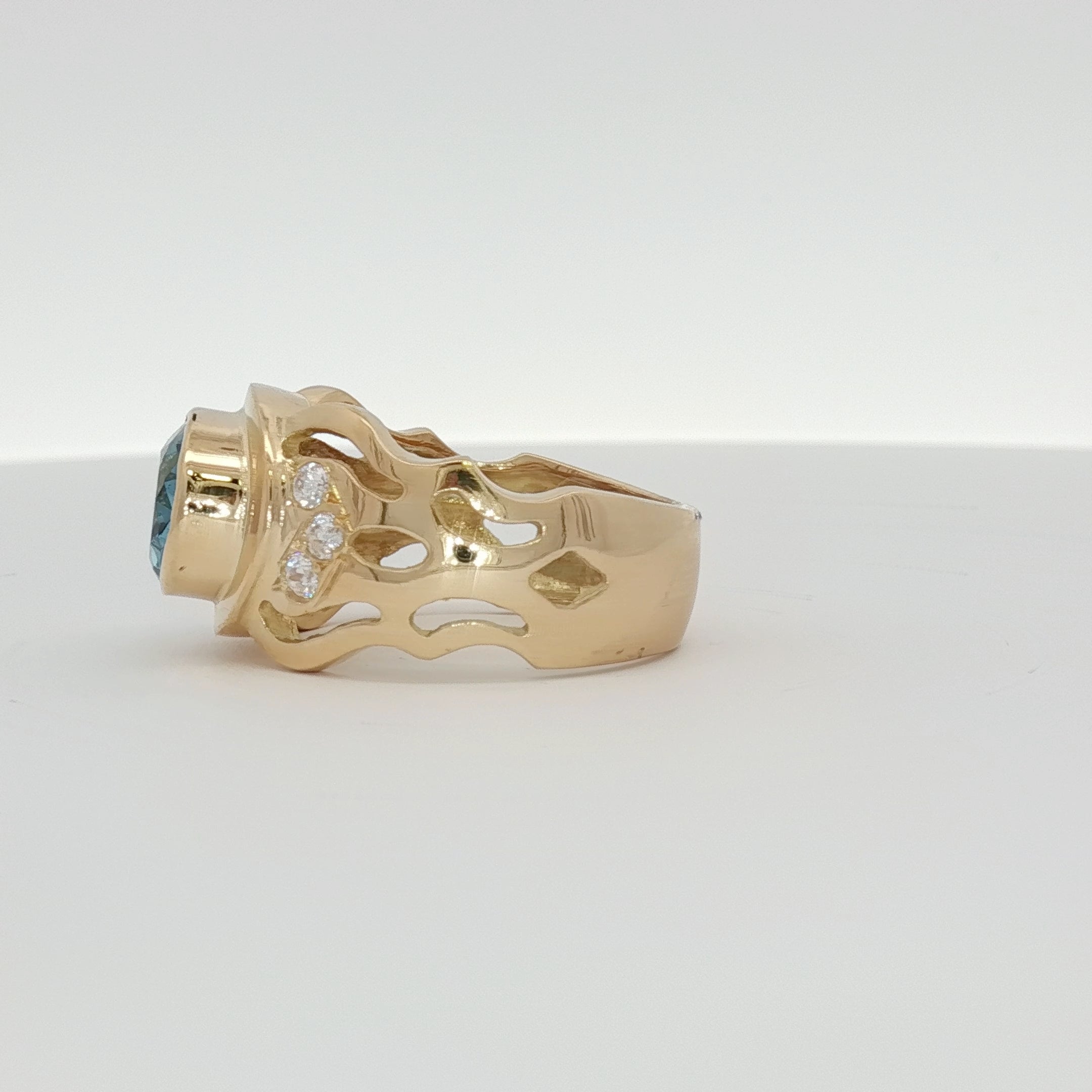 18K yellow gold oval blue gemstone and diamond ring with intricate band design, showcasing luxurious jewelry craftsmanship.