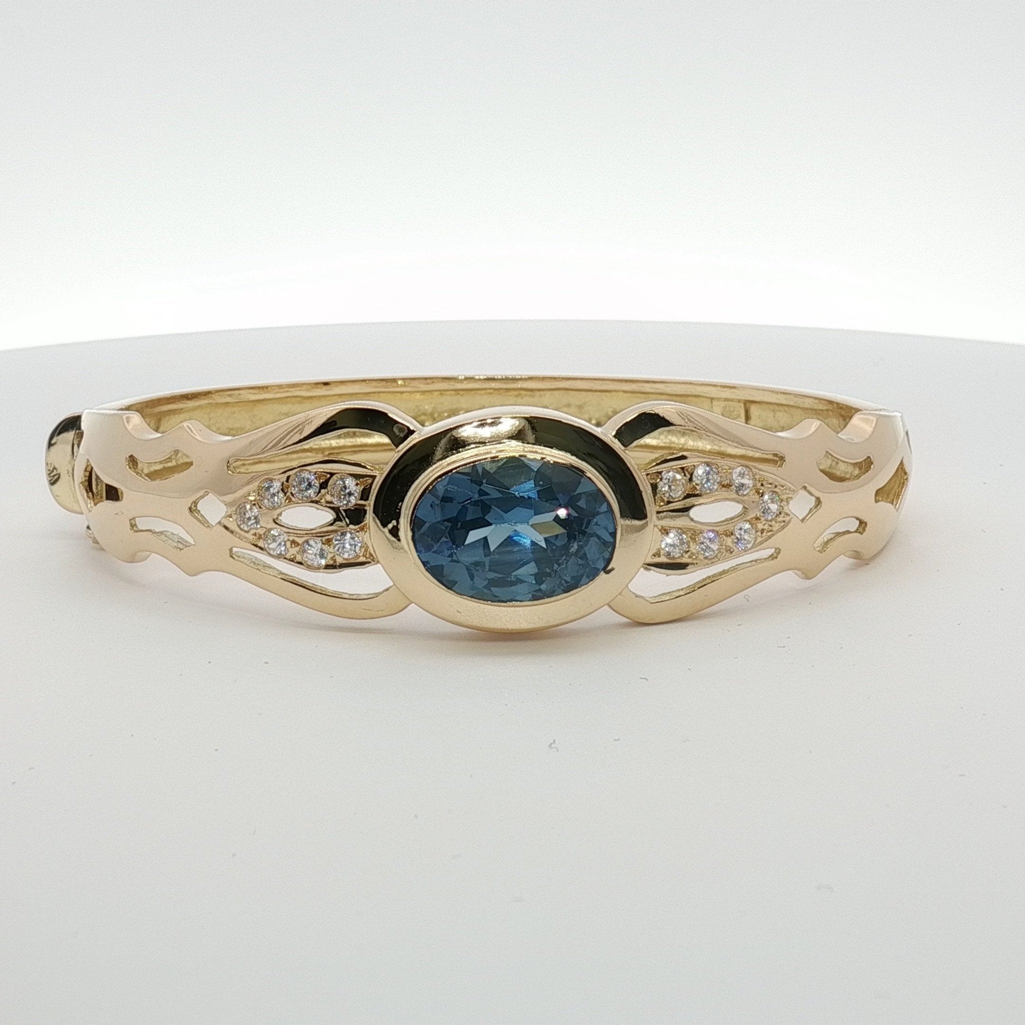 18K yellow gold cuff bracelet with blue gemstone accents, elegant jewelry piece by Gold & Beyond.