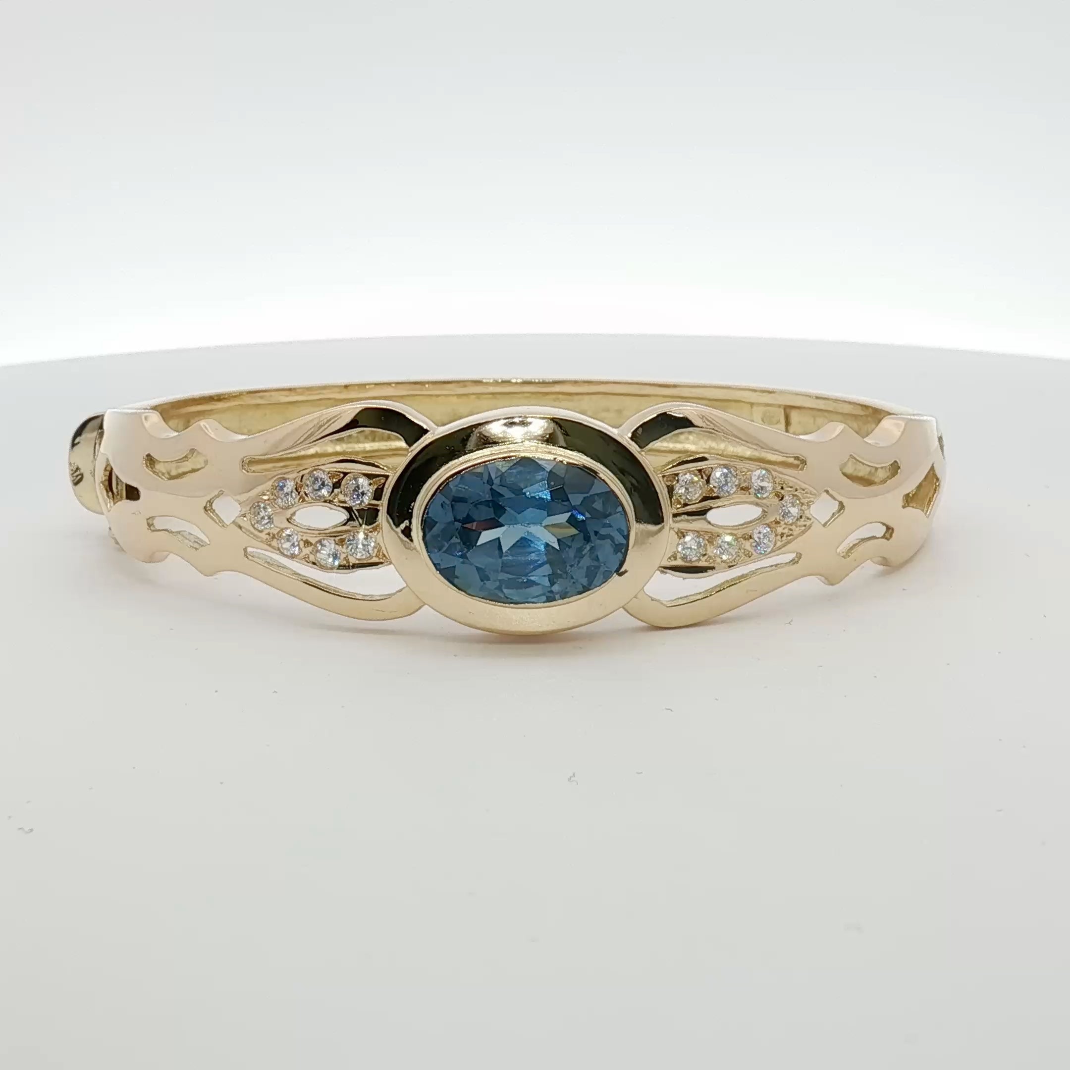18K yellow gold cuff bracelet with blue gemstones, elegant jewelry piece featuring intricate design and vibrant gemstone accents.