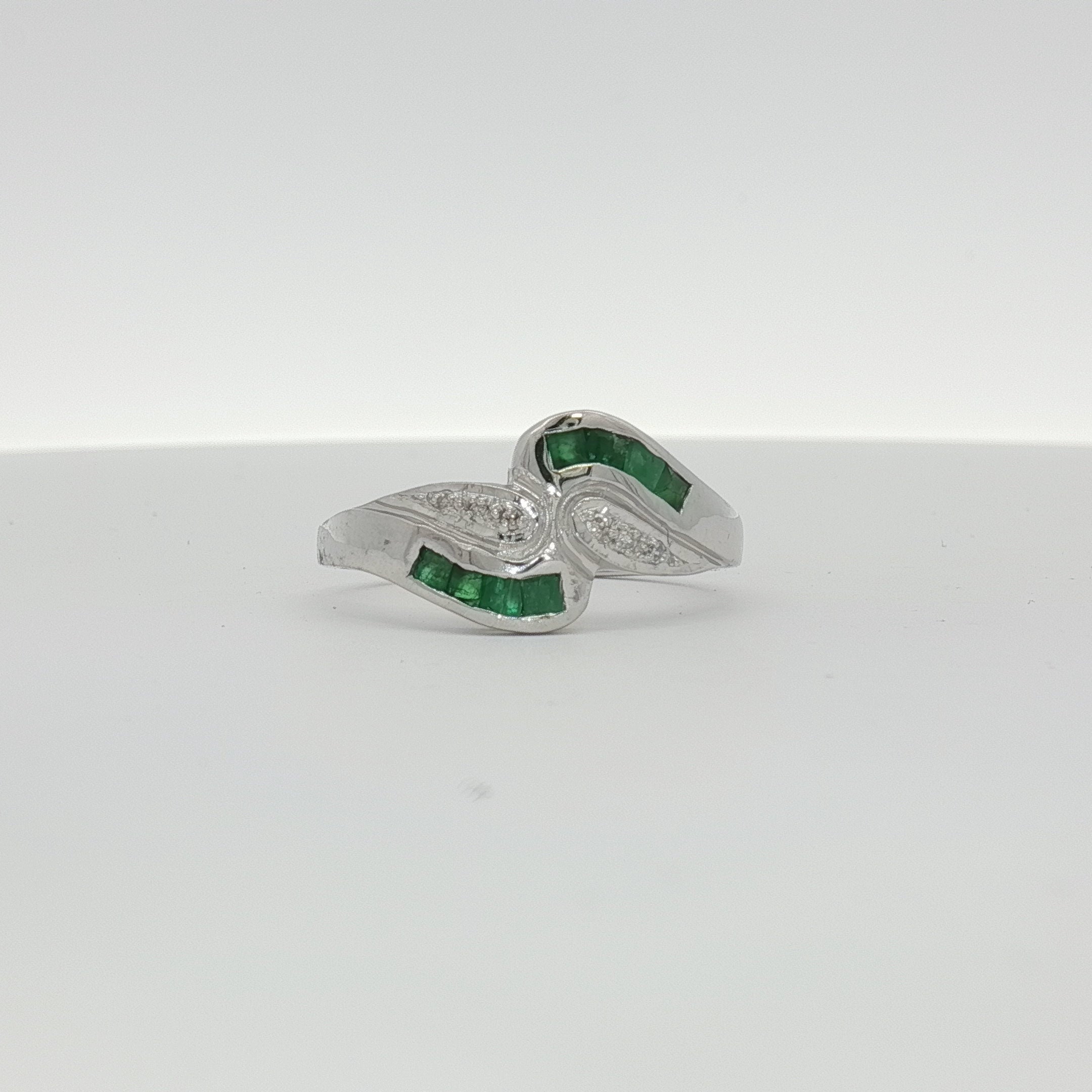 14K white gold emerald and diamond bypass ring with intricate design, showcasing sparkling gemstones and elegant craftsmanship.
