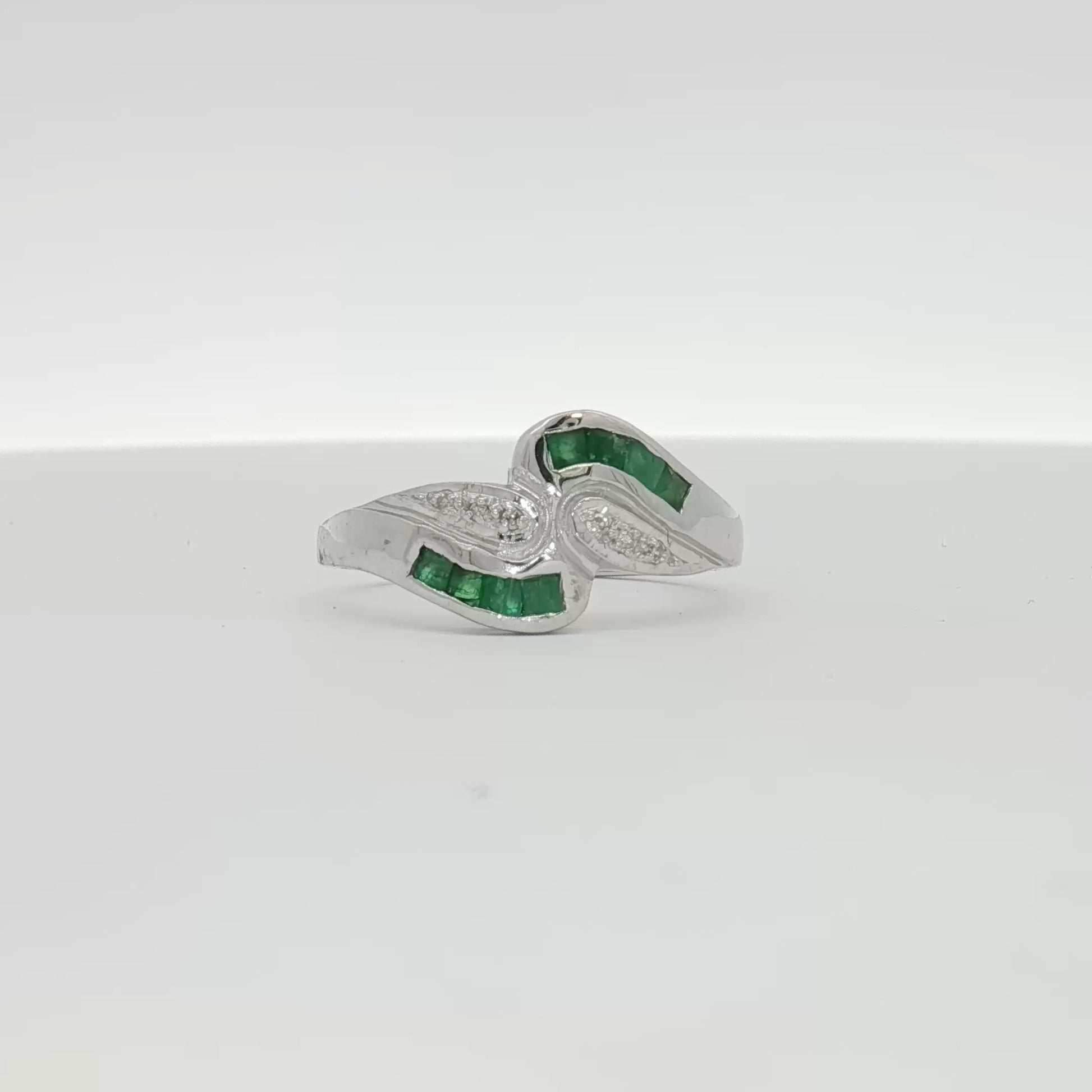 14K white gold emerald and diamond bypass ring, showcasing a elegant design with sparkling gemstones and intricate craftsmanship.