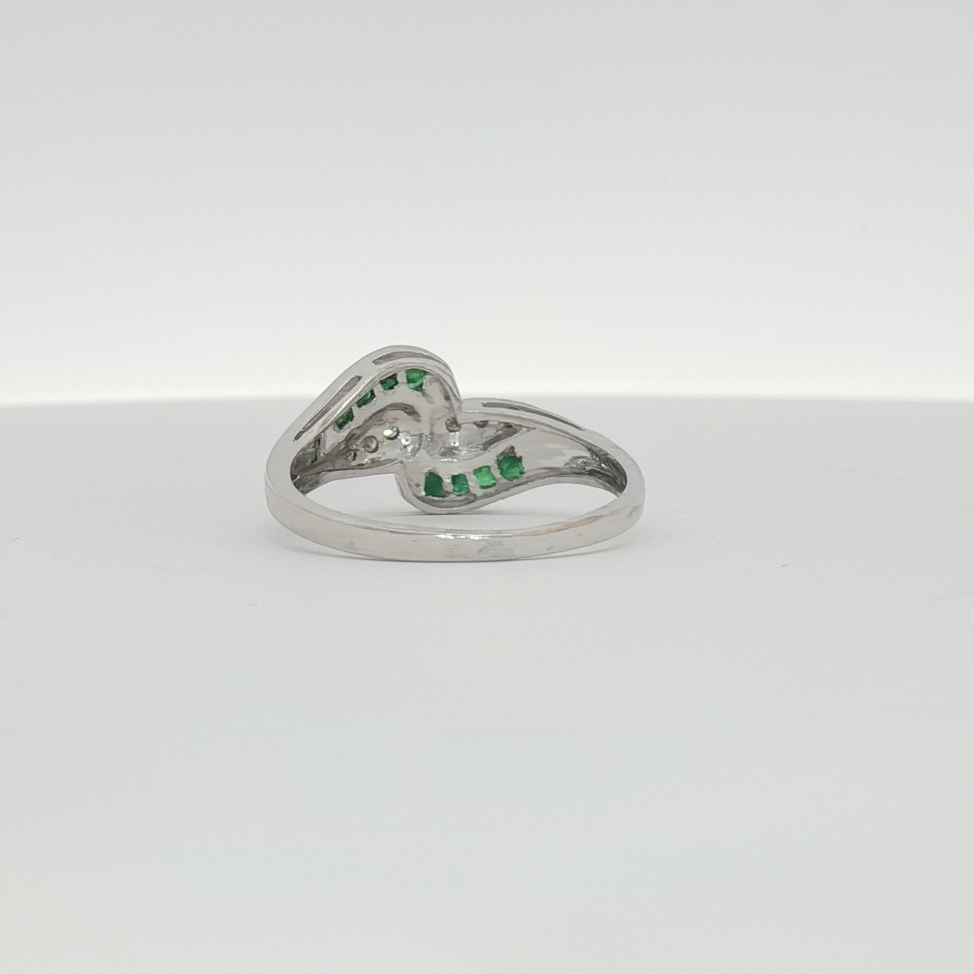 14K white gold emerald and diamond bypass ring with intricate design, showcasing sparkling gemstones and elegant craftsmanship.