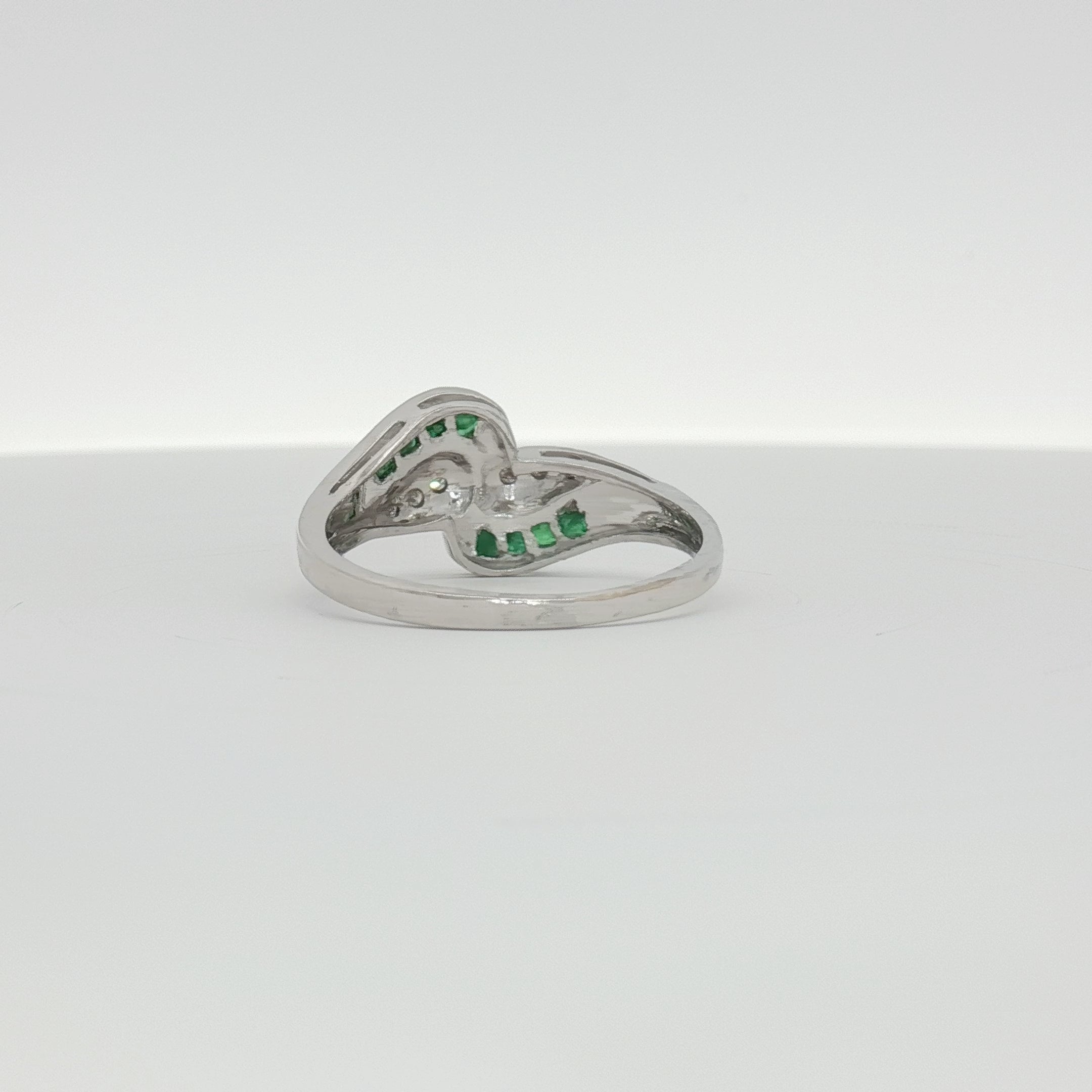 14K white gold emerald and diamond bypass ring with intricate design, showcasing sparkling gemstones and elegant craftsmanship.