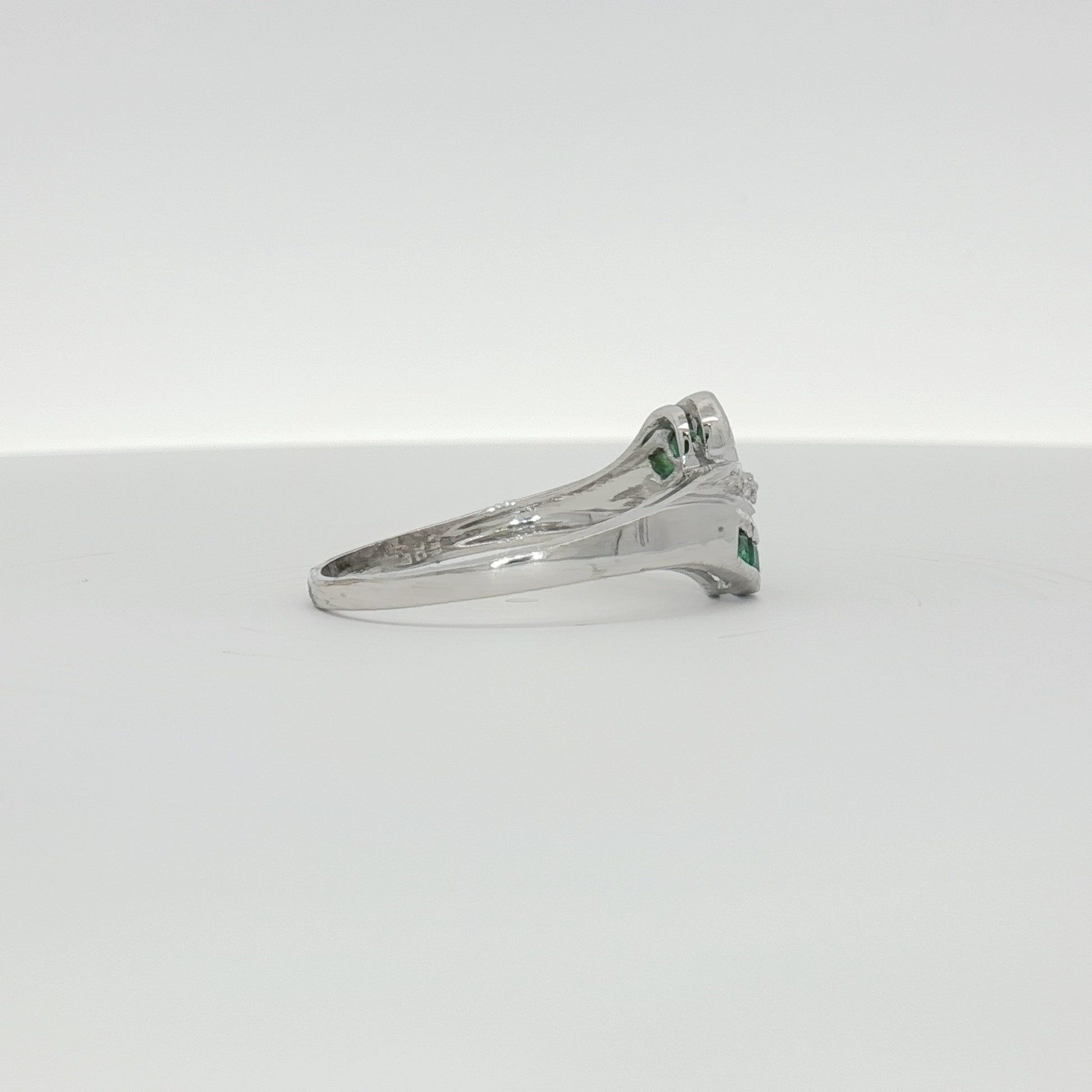 14K white gold emerald and diamond bypass ring featuring a sleek design and sparkling gemstone accents.