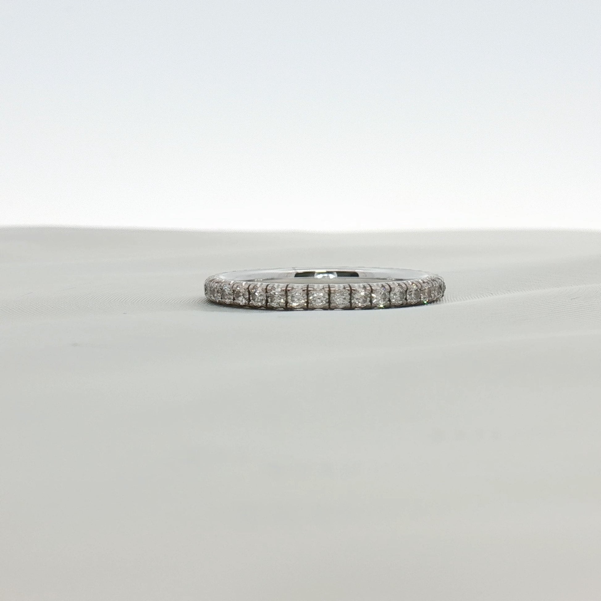 Cartier Love Eternity diamond band ring with gold setting, showcasing a continuous row of sparkling diamonds on a sleek jewelry piece.