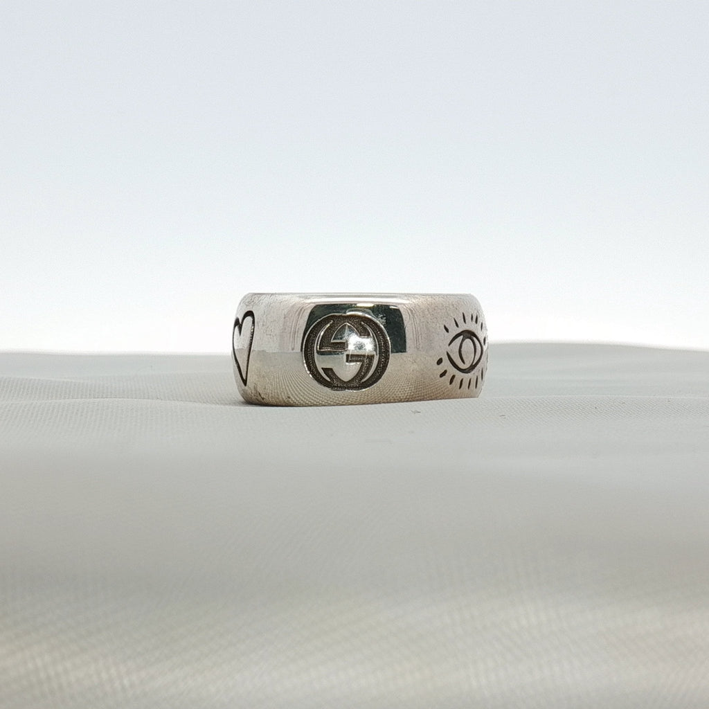Gucci Blind for Love sterling silver ring featuring an engraved motif band in size 6, displayed on a soft fabric background.