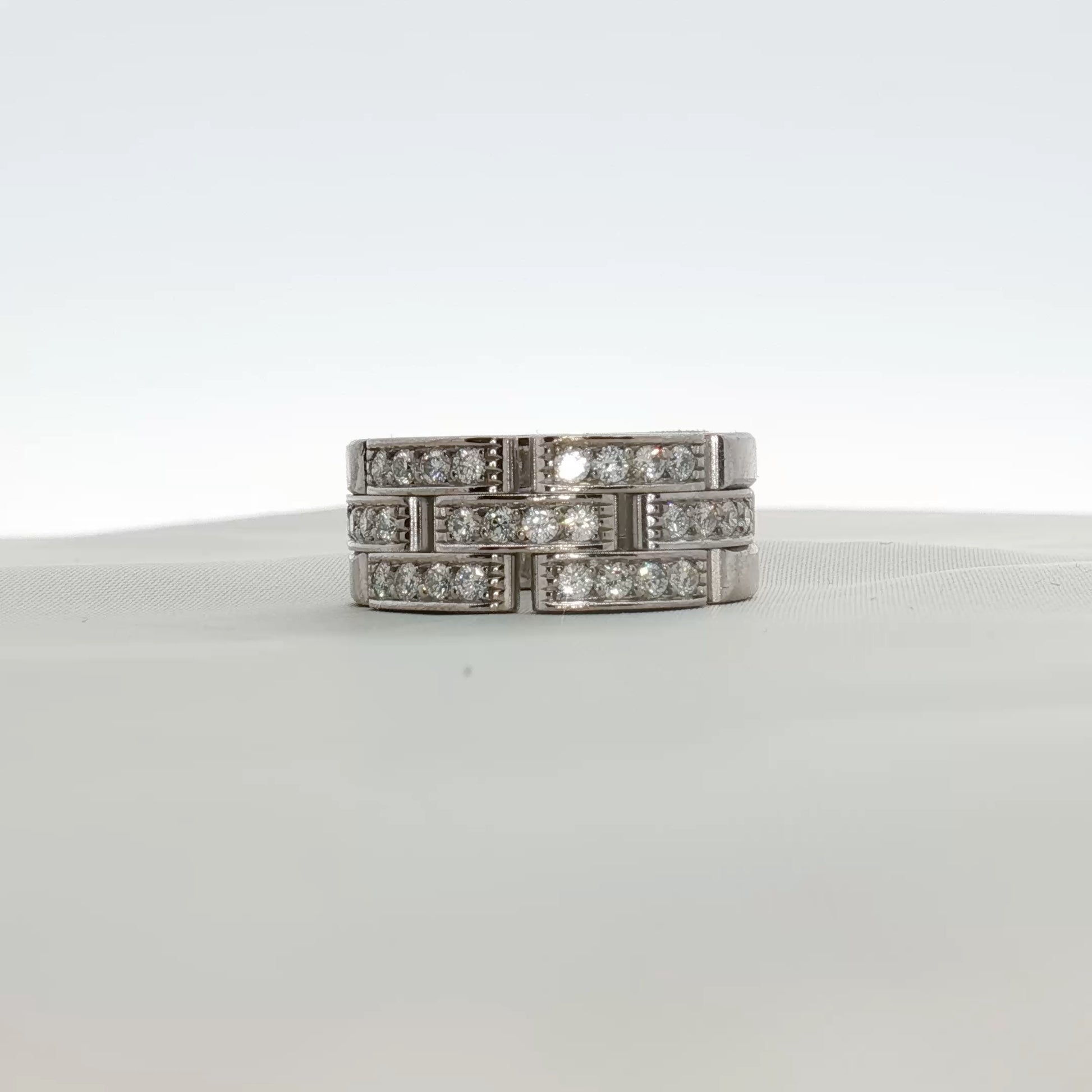 Cartier Maillon diamond ring with gold band, featuring intricate linking and sparkling diamonds on a jewelry display.