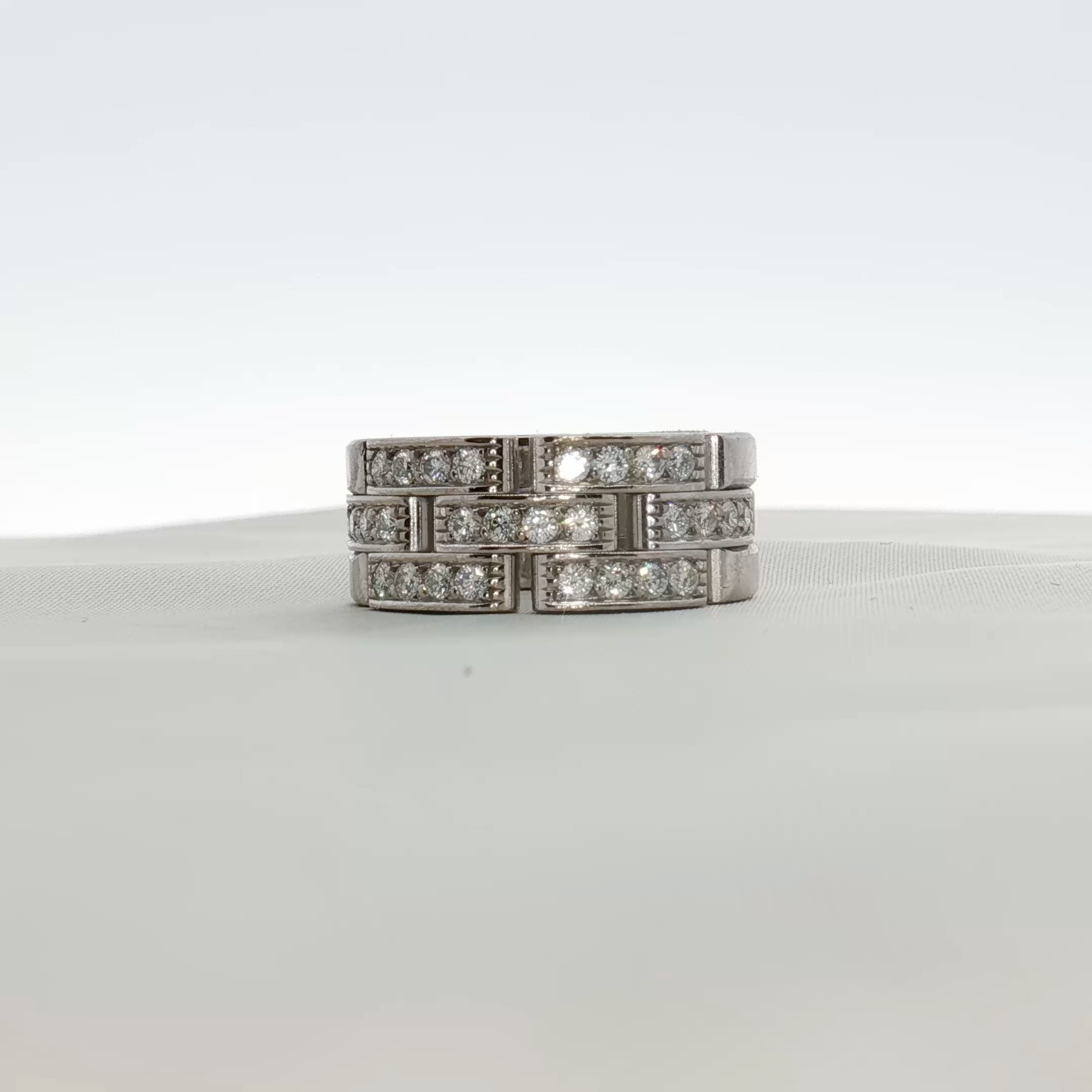 Cartier Maillon diamond ring with gold band, featuring intricate linking and sparkling diamonds on a jewelry display.
