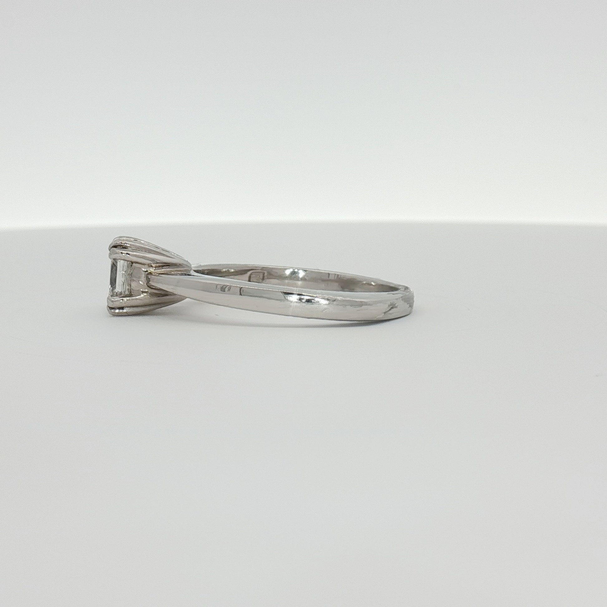 Platinum diamond solitaire engagement ring featuring a central sparkling diamond set on a sleek band.