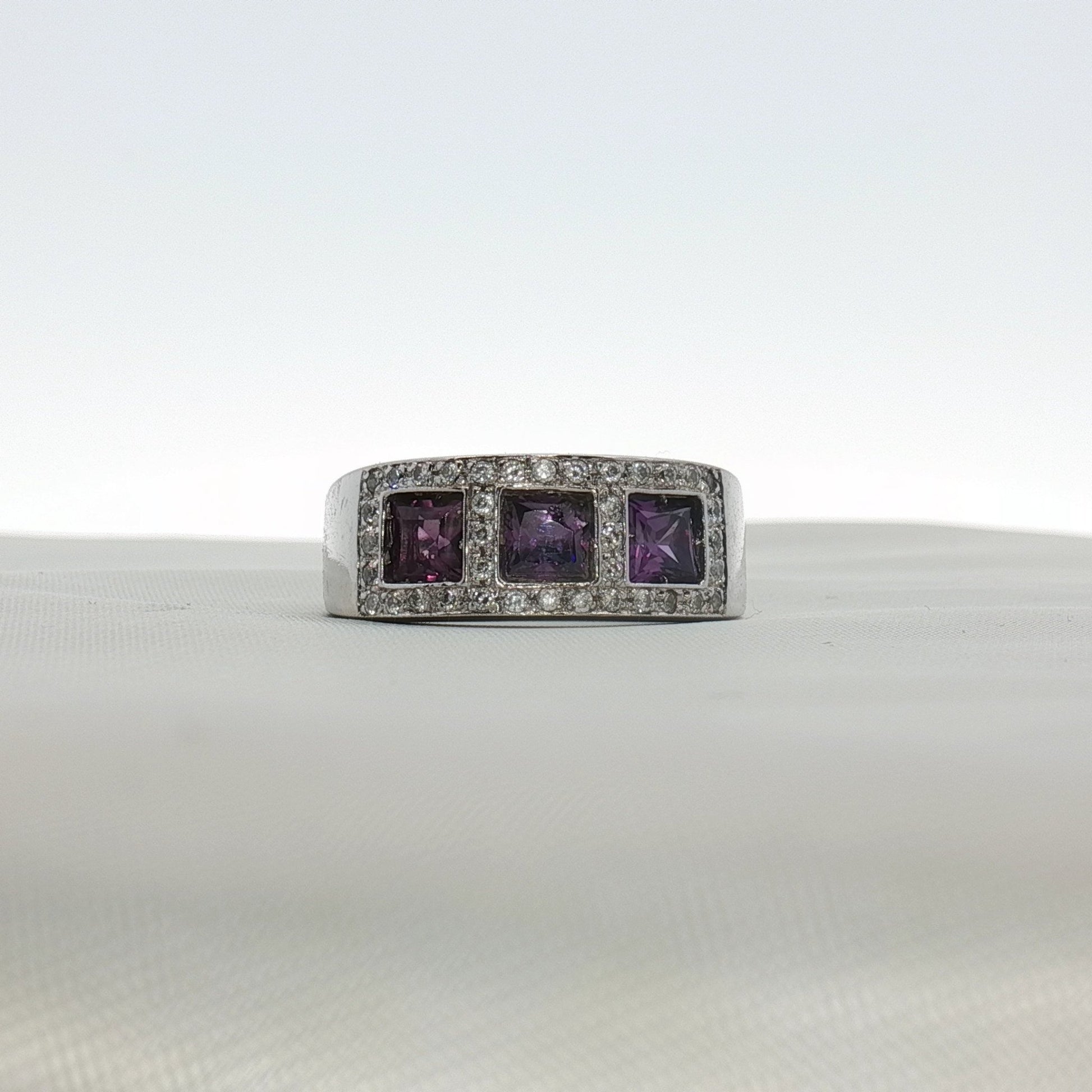 Three-stone diamond and purple gemstone ring by Gold & Beyond, showcasing sparkling diamonds and vibrant purple stones in elegant jewelry.