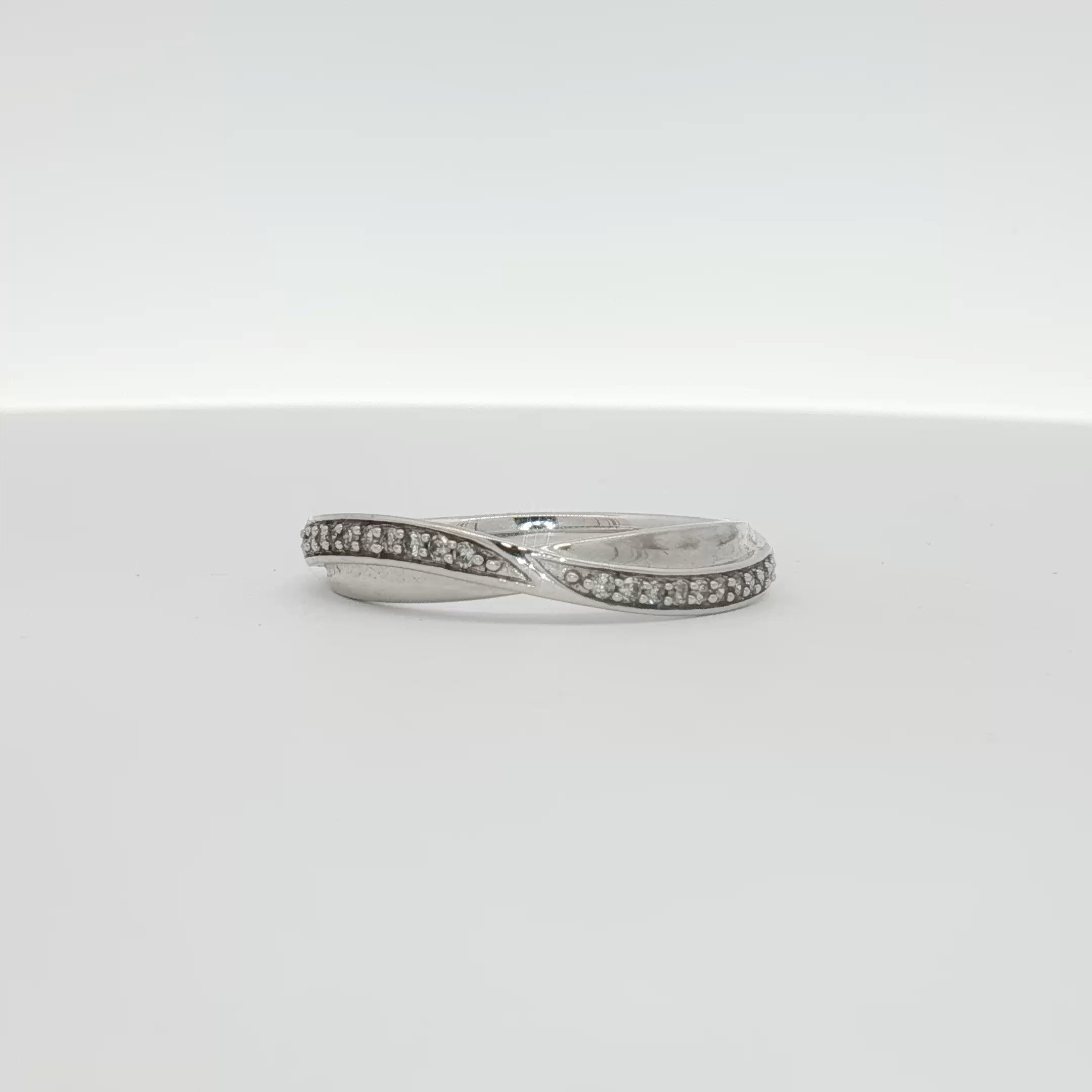 Elegant 10K white gold diamond twist band ring showcasing sparkling diamonds and intricate design from Gold & Beyond jewelry collection.
