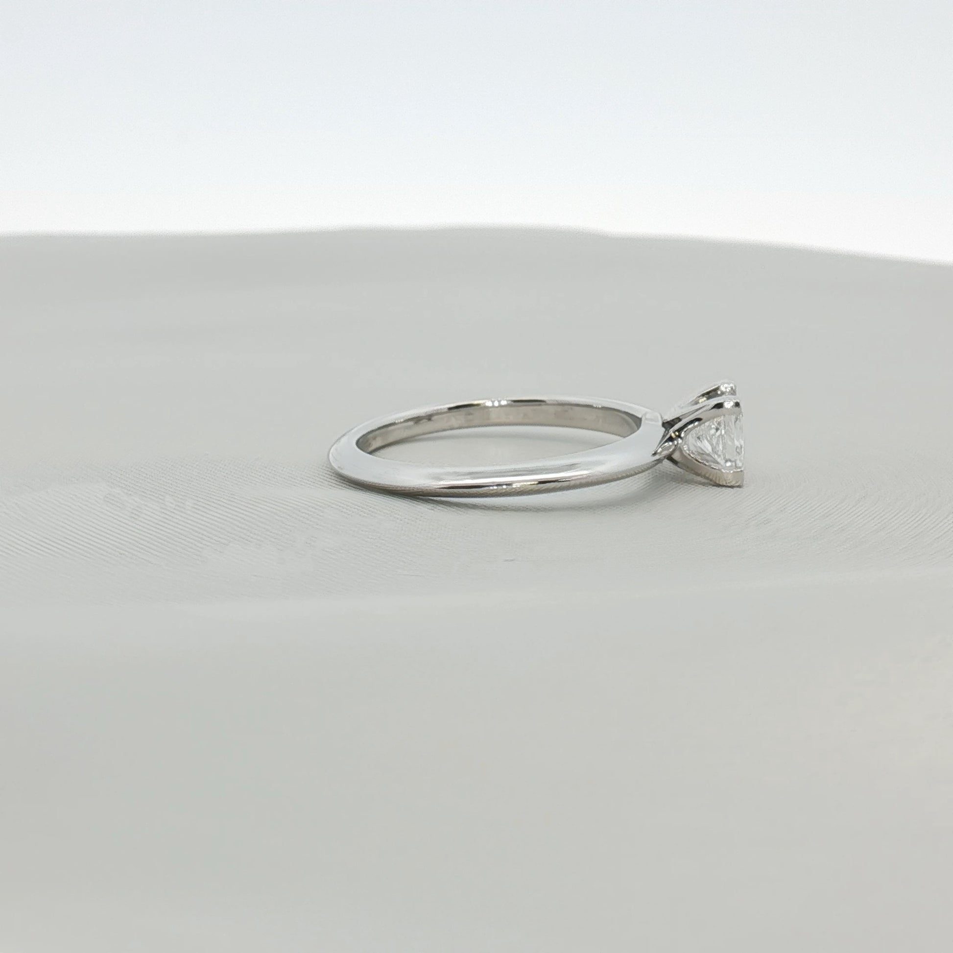 Tiffany & Co. platinum diamond solitaire ring with a single sparkling diamond on a sleek band.