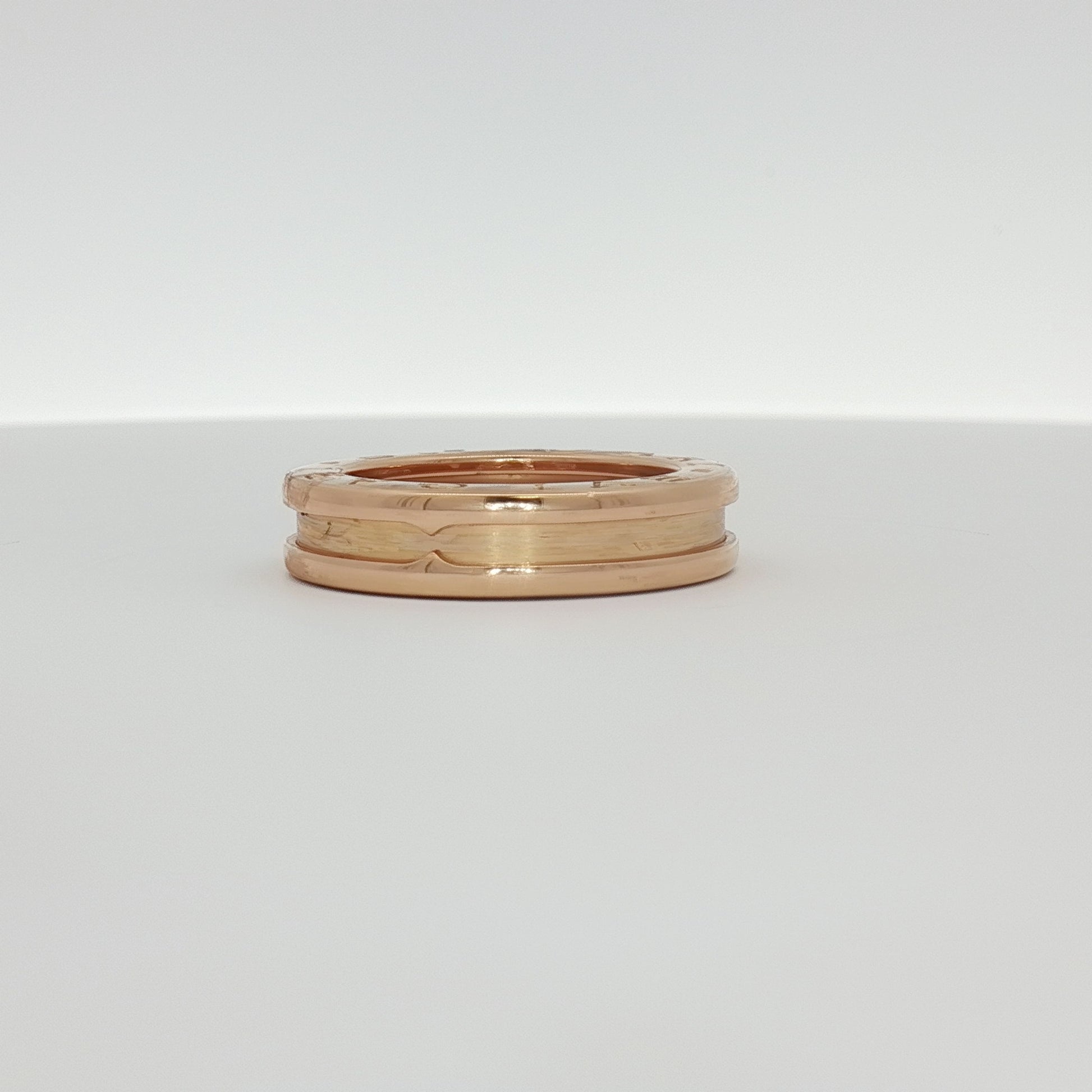 Bulgari B.Zero1 ring in gold, showcasing its iconic circular design with engraved branding, on a jewelry display.