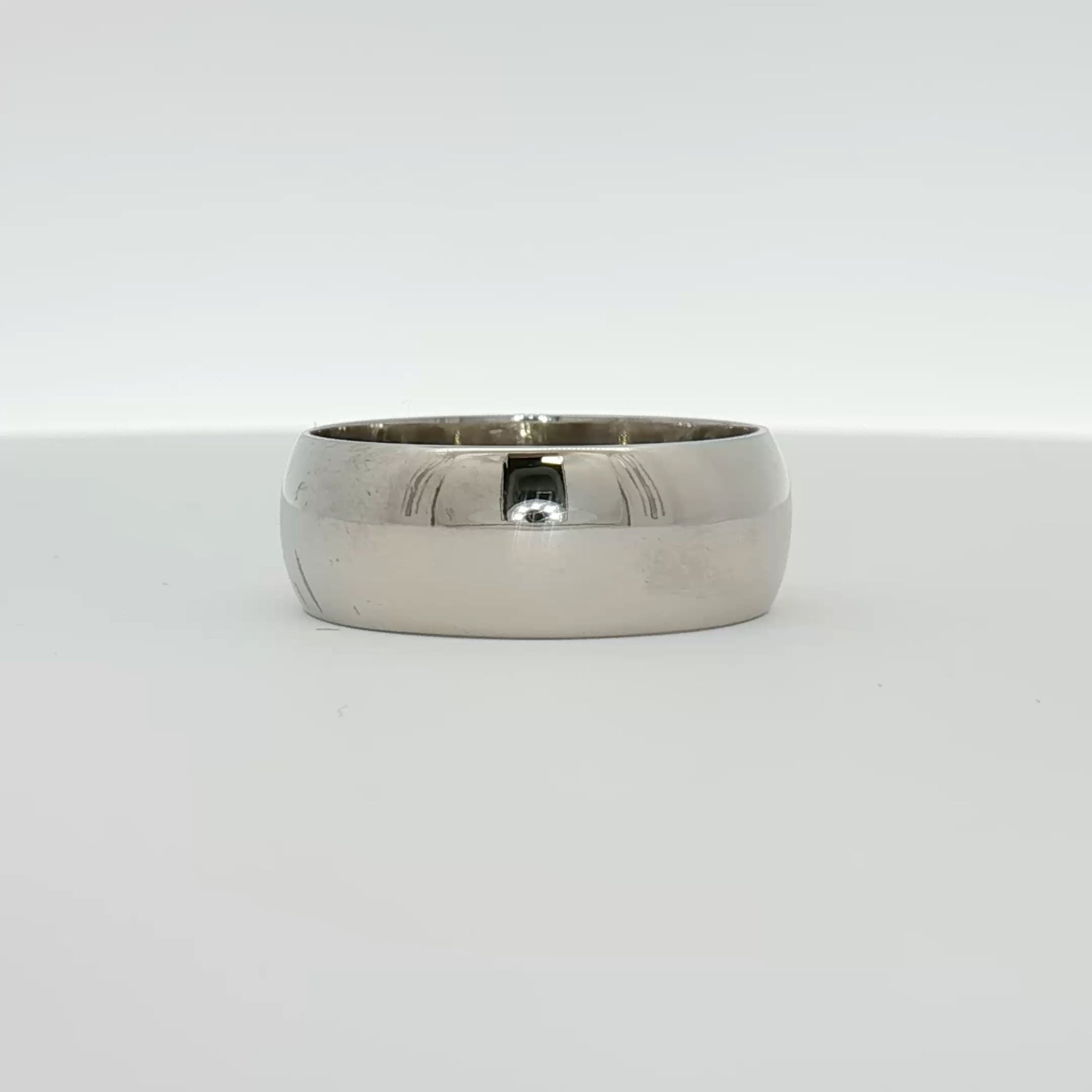 Elegant gold gentleman’s wedding band by Gold & Beyond, showcasing a smooth, polished jewelry design on a neutral background.