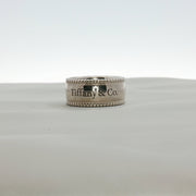 Sterling silver Tiffany & Co. Milgrain band jewelry with intricate textured detailing, displayed on a neutral background.