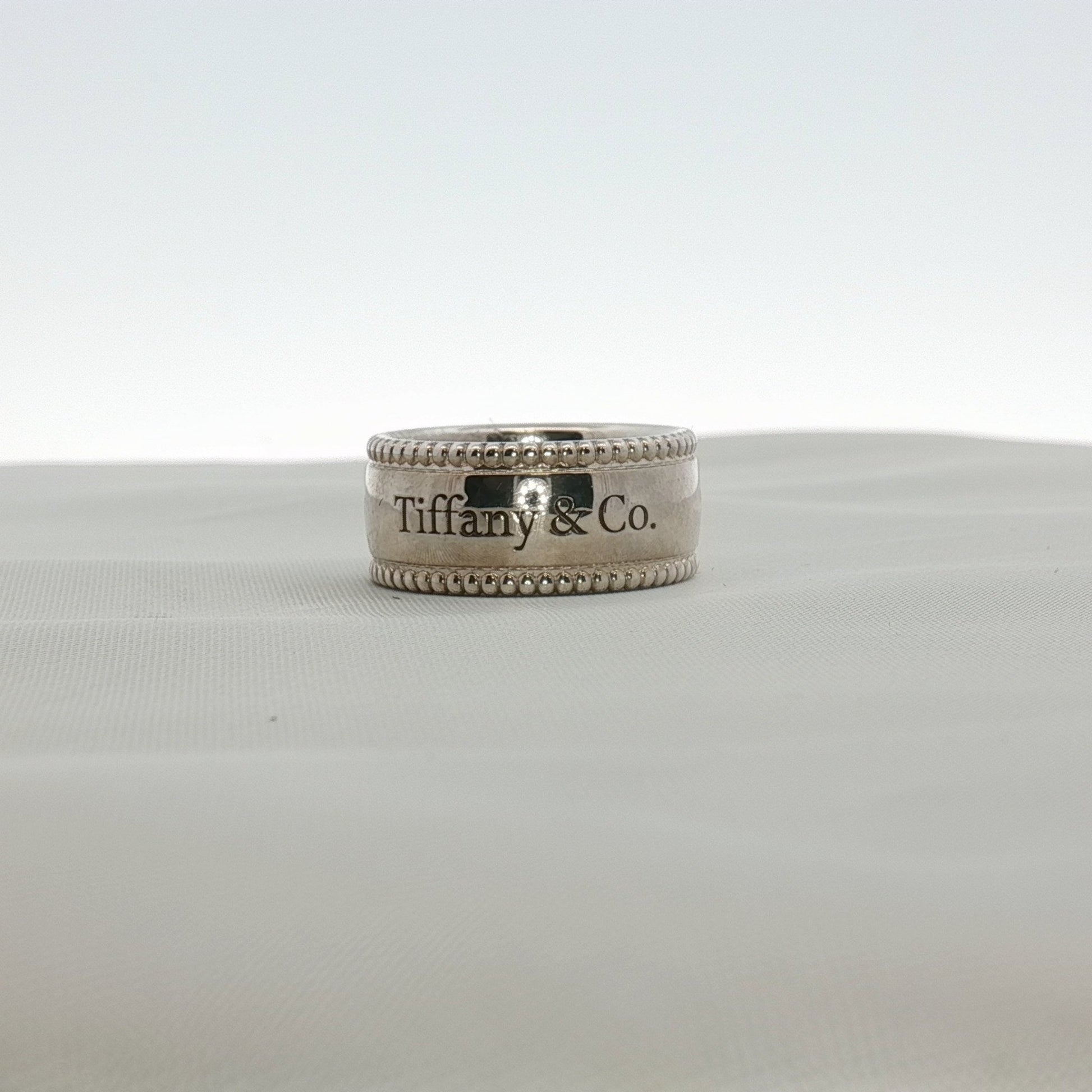 Sterling silver Tiffany & Co. Milgrain band jewelry with intricate textured detailing, displayed on a neutral background.