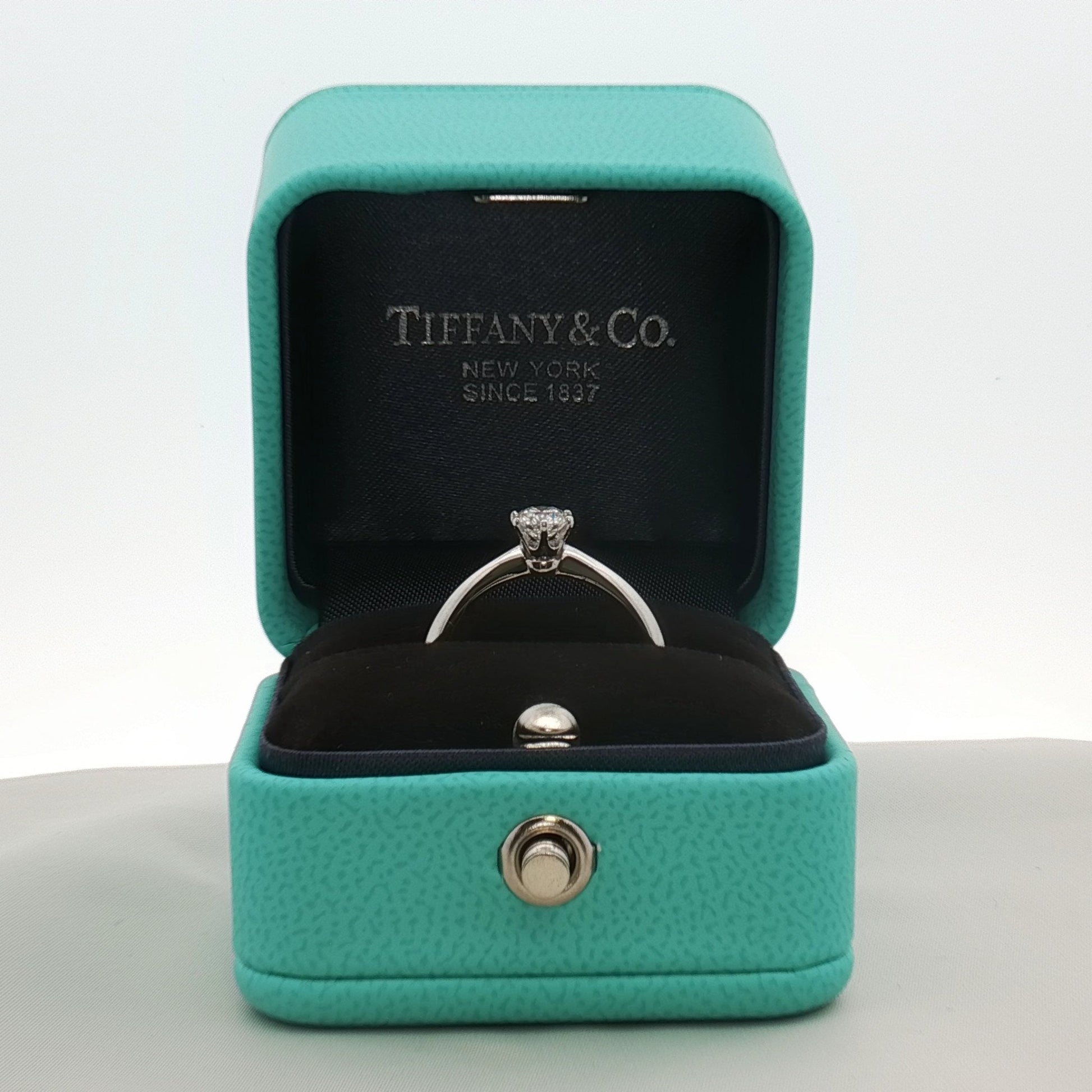 Platinum solitaire engagement ring by Gold & Beyond featuring a central diamond set in a sleek Tiffany & Co. style jewelry design.