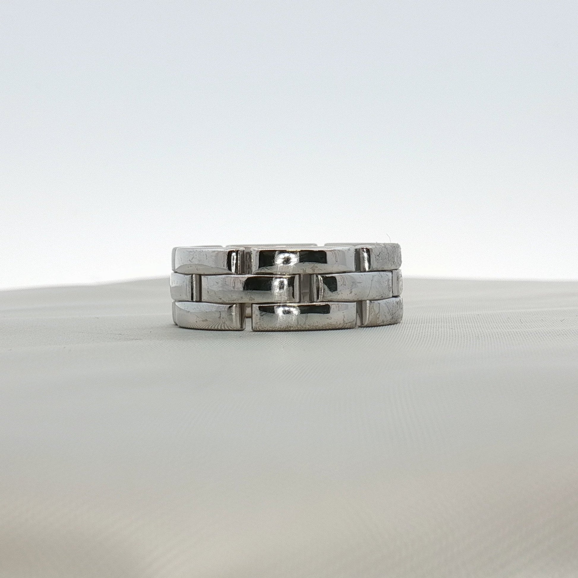 Cartier Maillon Band ring in gold, featuring a linked chain design, displayed on a jewelry stand.