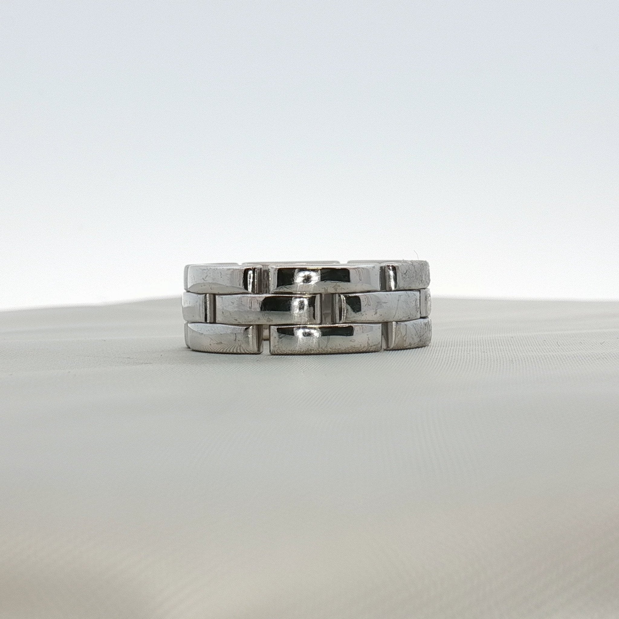 Cartier Maillon Band ring in gold, featuring a linked chain design, displayed on a jewelry stand.