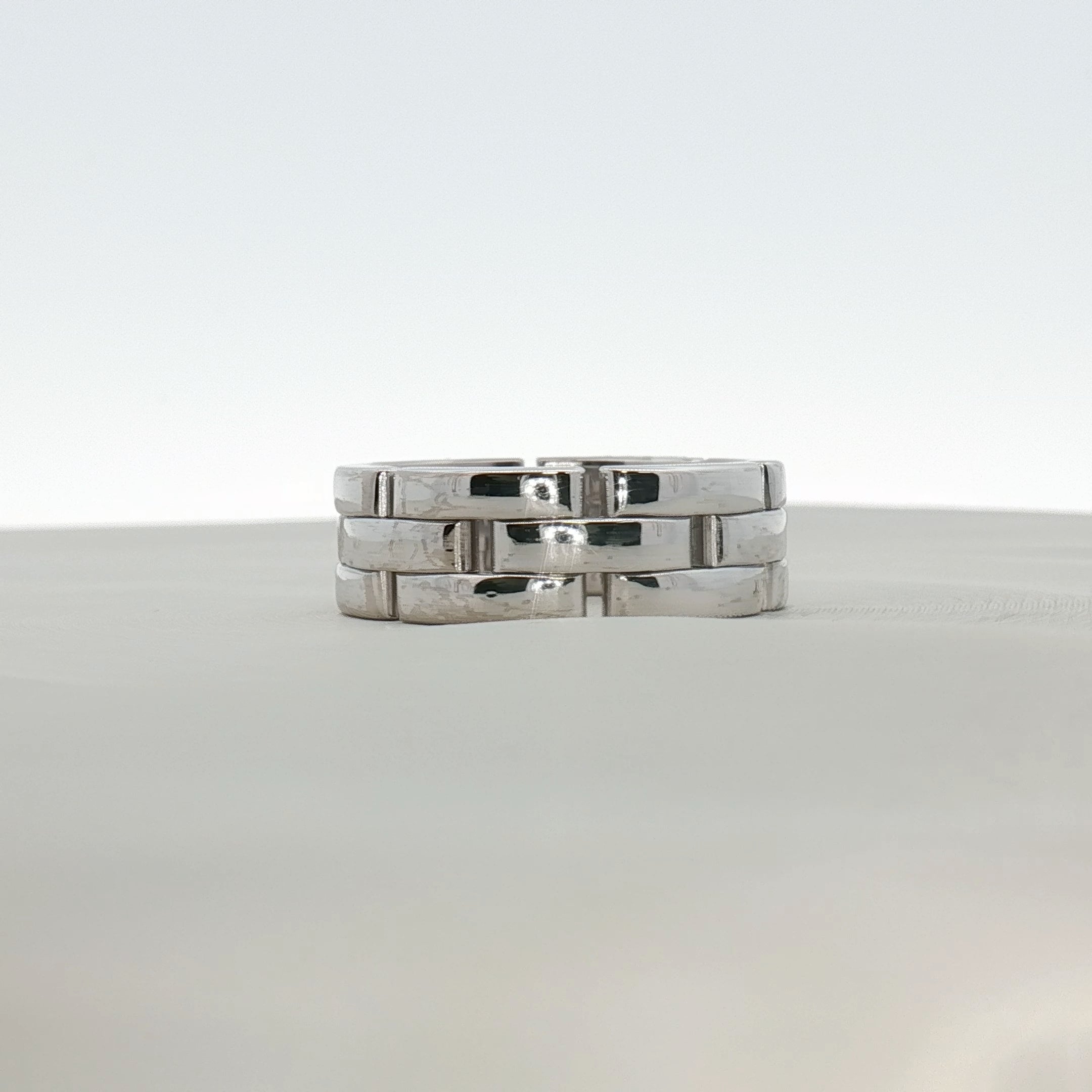 Cartier Maillon Band ring in gold jewelry displayed on a neutral background, showcasing its linked chain design and craftsmanship.