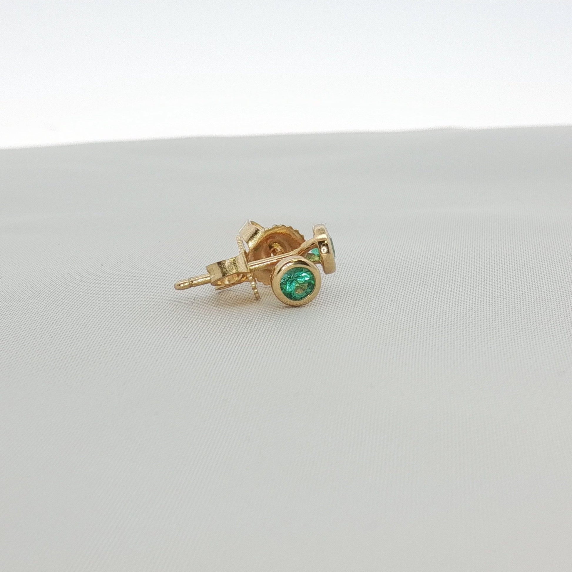 Tiffany & Co. 18K yellow gold emerald stud earrings with sparkling green gemstones and classic jewelry design.