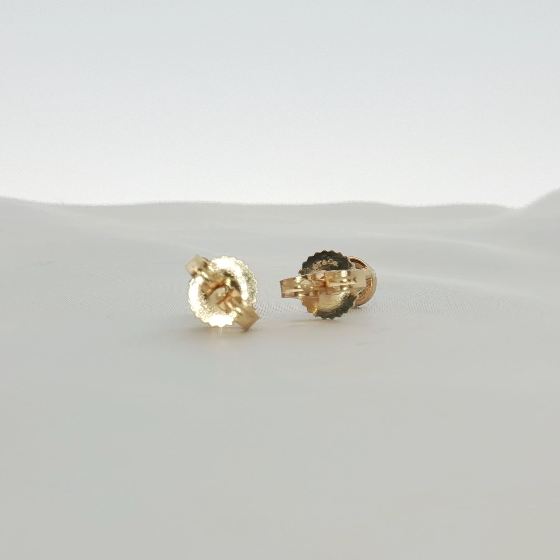 Gold & Beyond Tiffany & Co. 18K yellow gold emerald stud earrings with vibrant green gemstones and classic jewelry design.