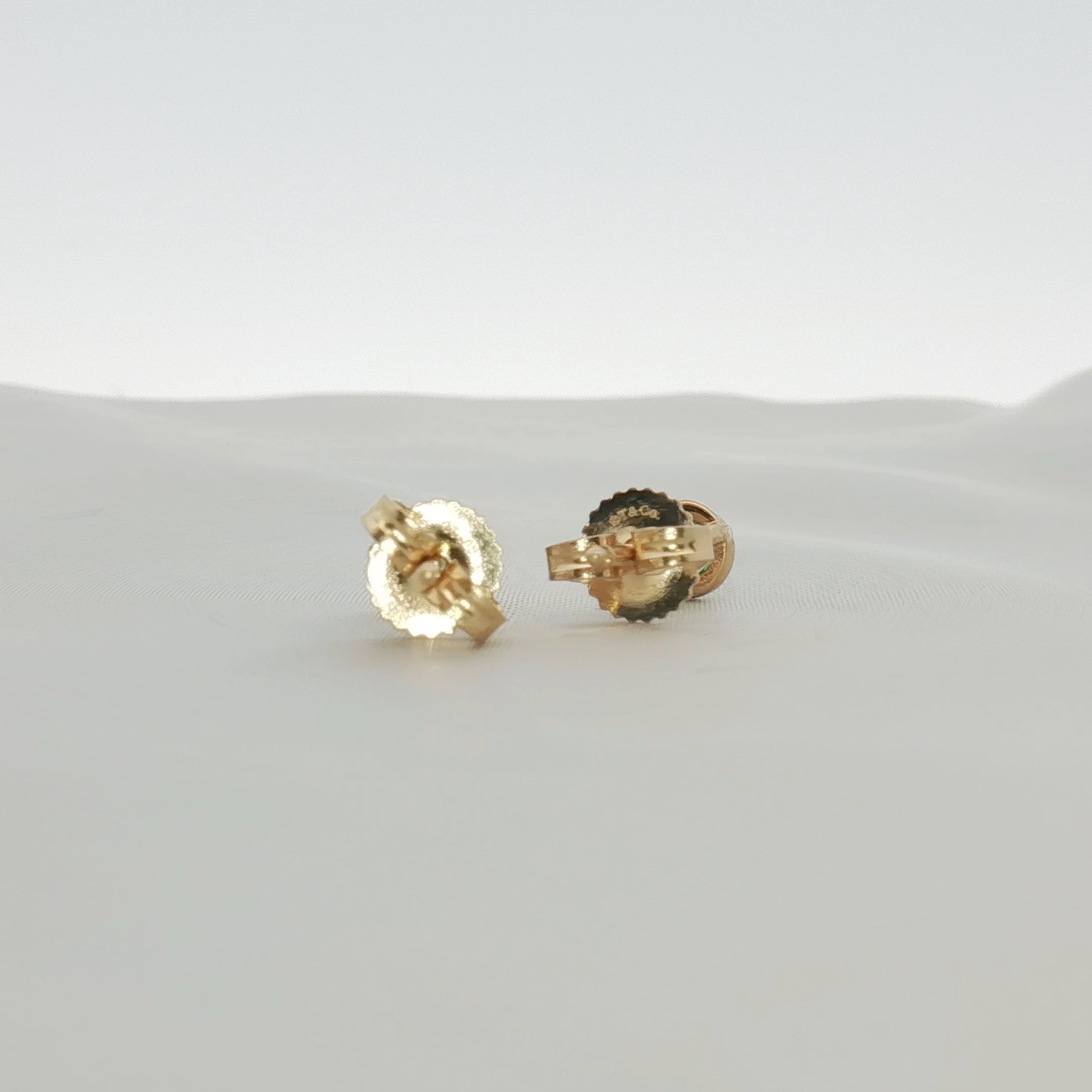 Gold & Beyond Tiffany & Co. 18K yellow gold emerald stud earrings with vibrant green gemstones and classic jewelry design.