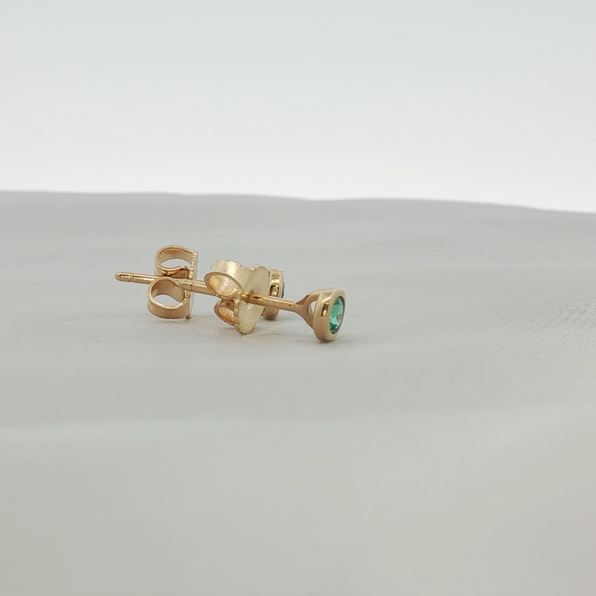 Tiffany & Co. 18K yellow gold emerald stud earrings, jewelry featuring vibrant green emerald gemstones on classic gold settings.