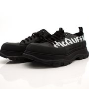 Alexander McQueen oversized sneakers in white with chunky soles and gold accents, styled as fashionable casual shoes.
