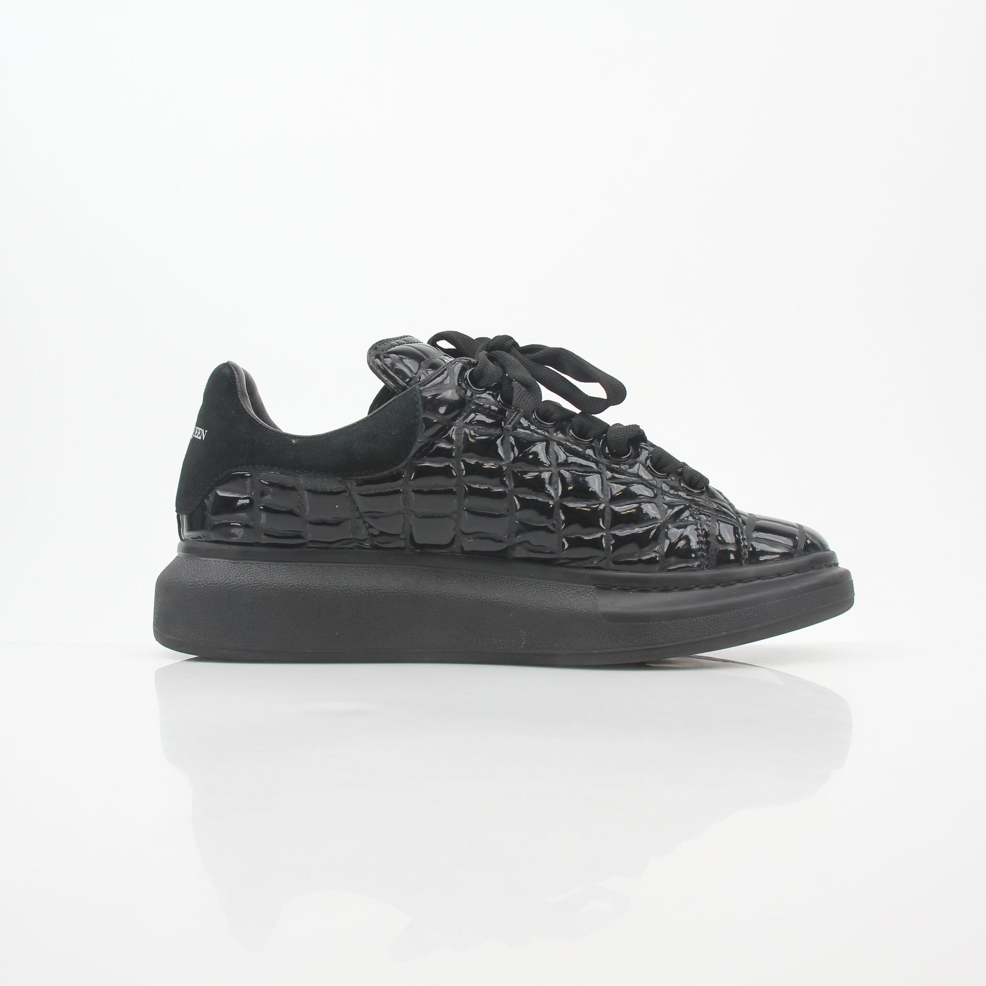 Alexander McQueen black croc-embossed oversized sneakers with chunky sole and bold design, displayed on a white background.