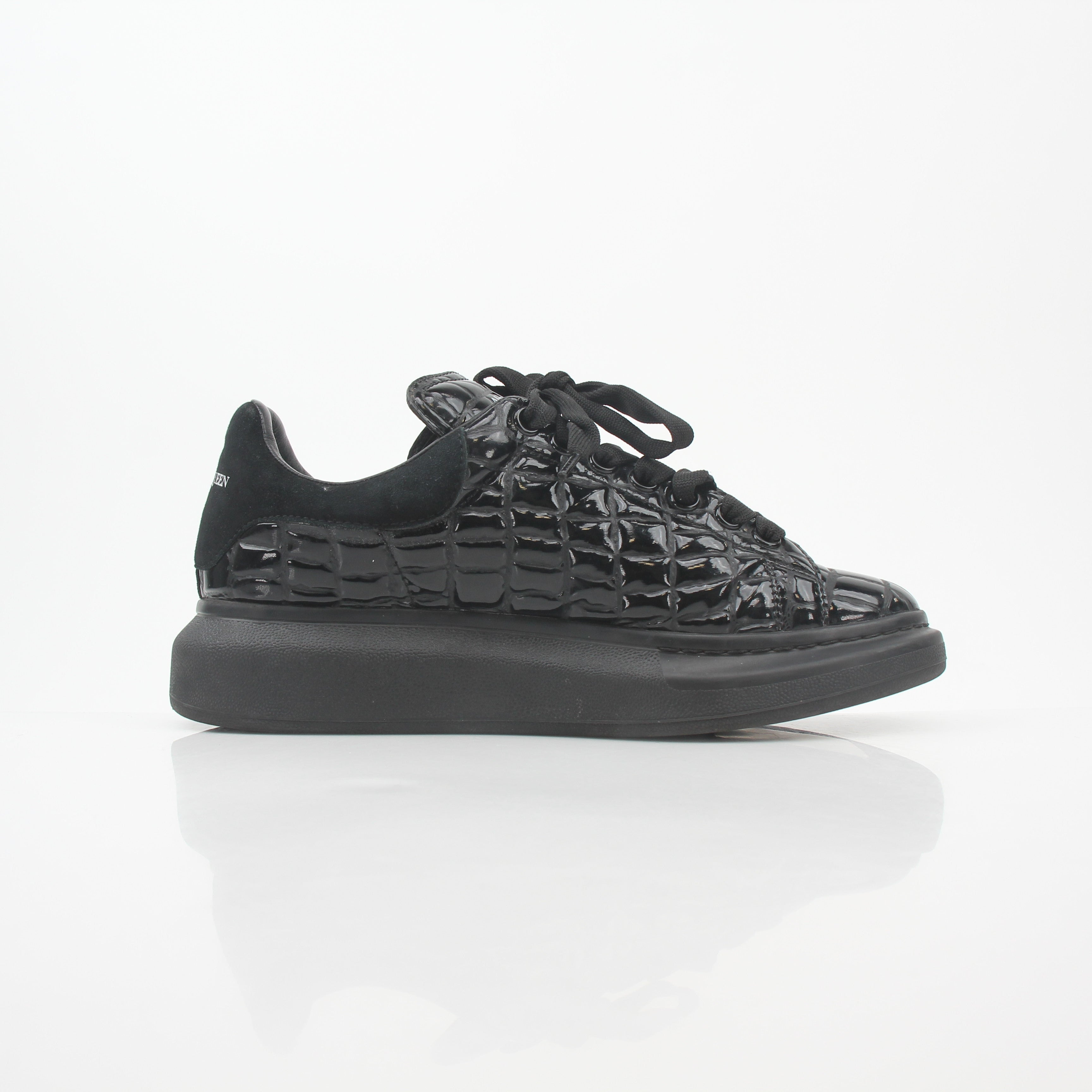 Alexander McQueen black croc-embossed oversized sneakers with chunky sole and bold design, displayed on a white background.