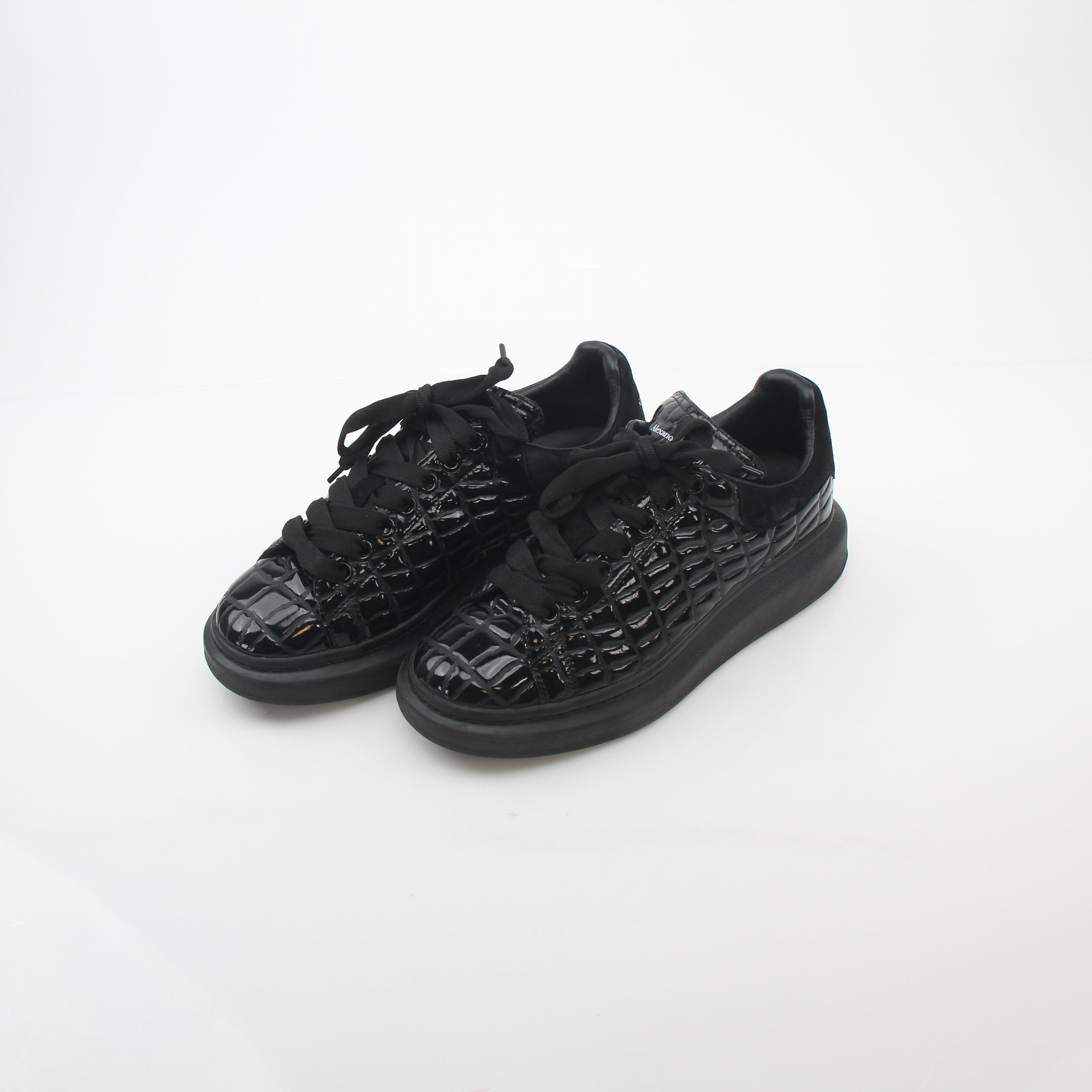 Black croc-embossed Alexander McQueen oversized sneakers with chunky soles and sleek design, styled for bold fashion statements.