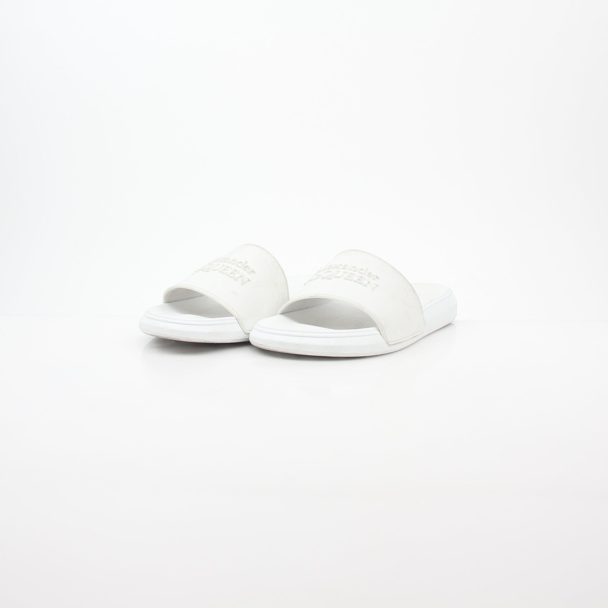 White Alexander McQueen logo pool slide sandals shown with open toe design and slip-on style on a flat surface.