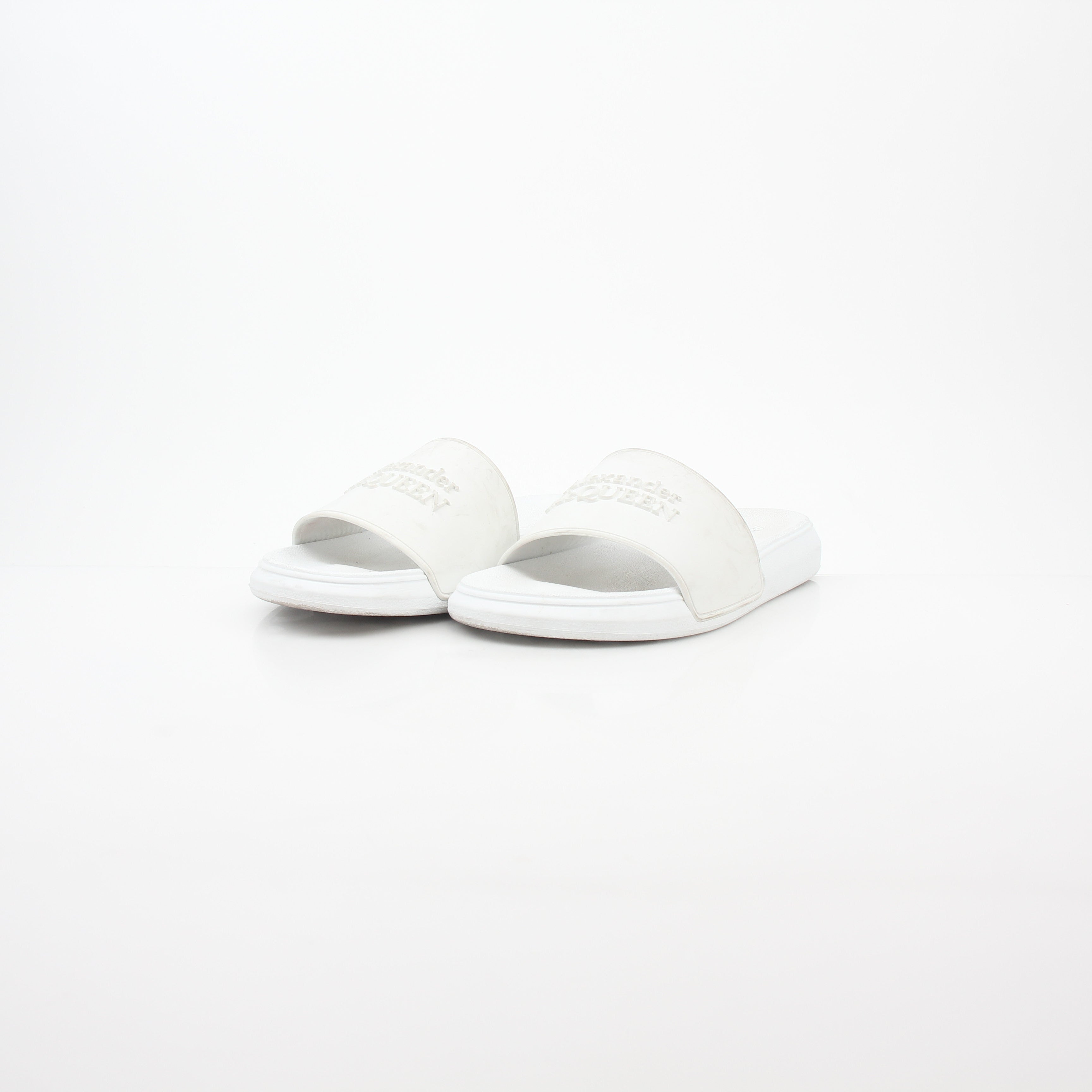 White Alexander McQueen logo pool slide sandals shown with open toe design and slip-on style on a flat surface.