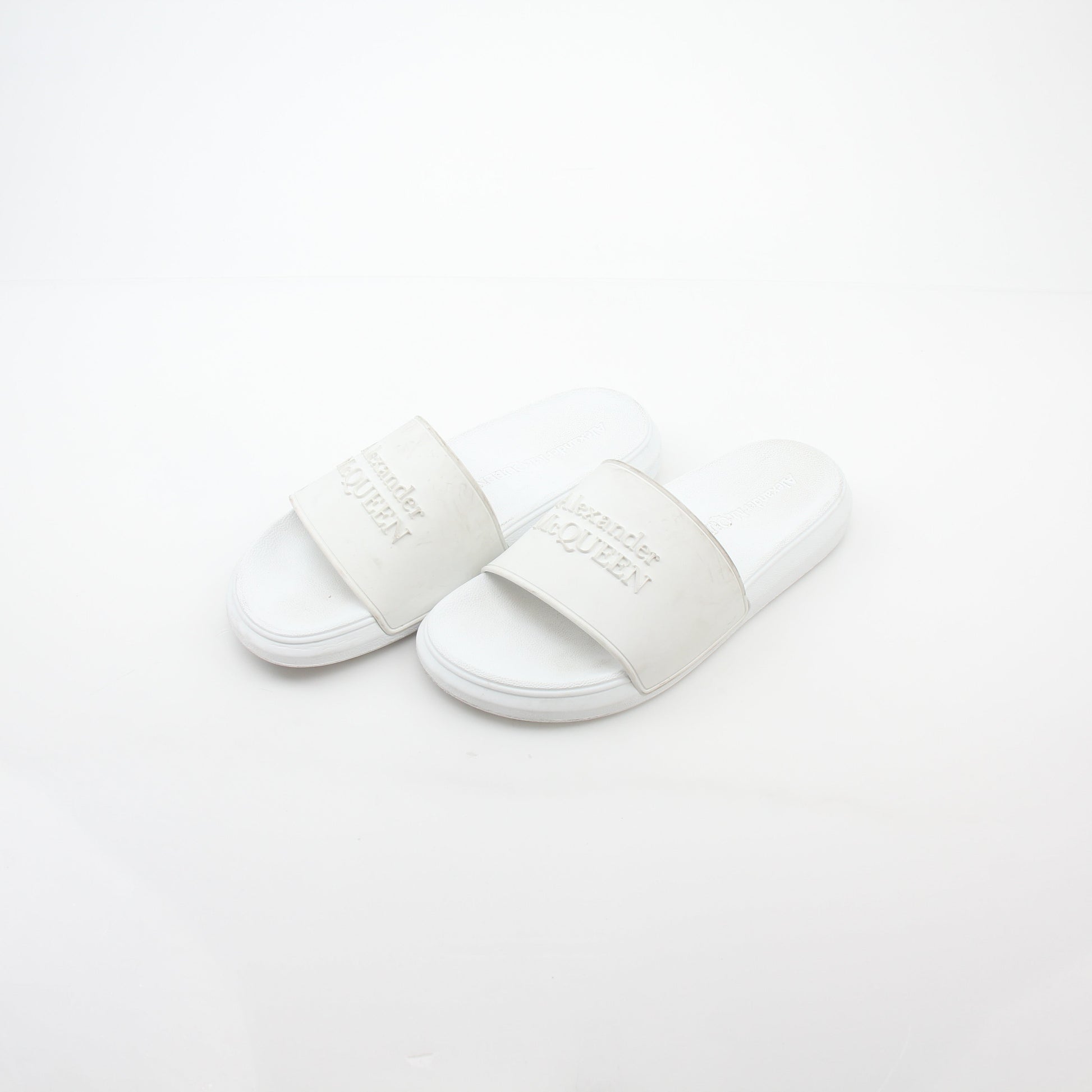 Alexander McQueen white logo pool slide sandals with open toe design and slip-on style, featuring branded straps.